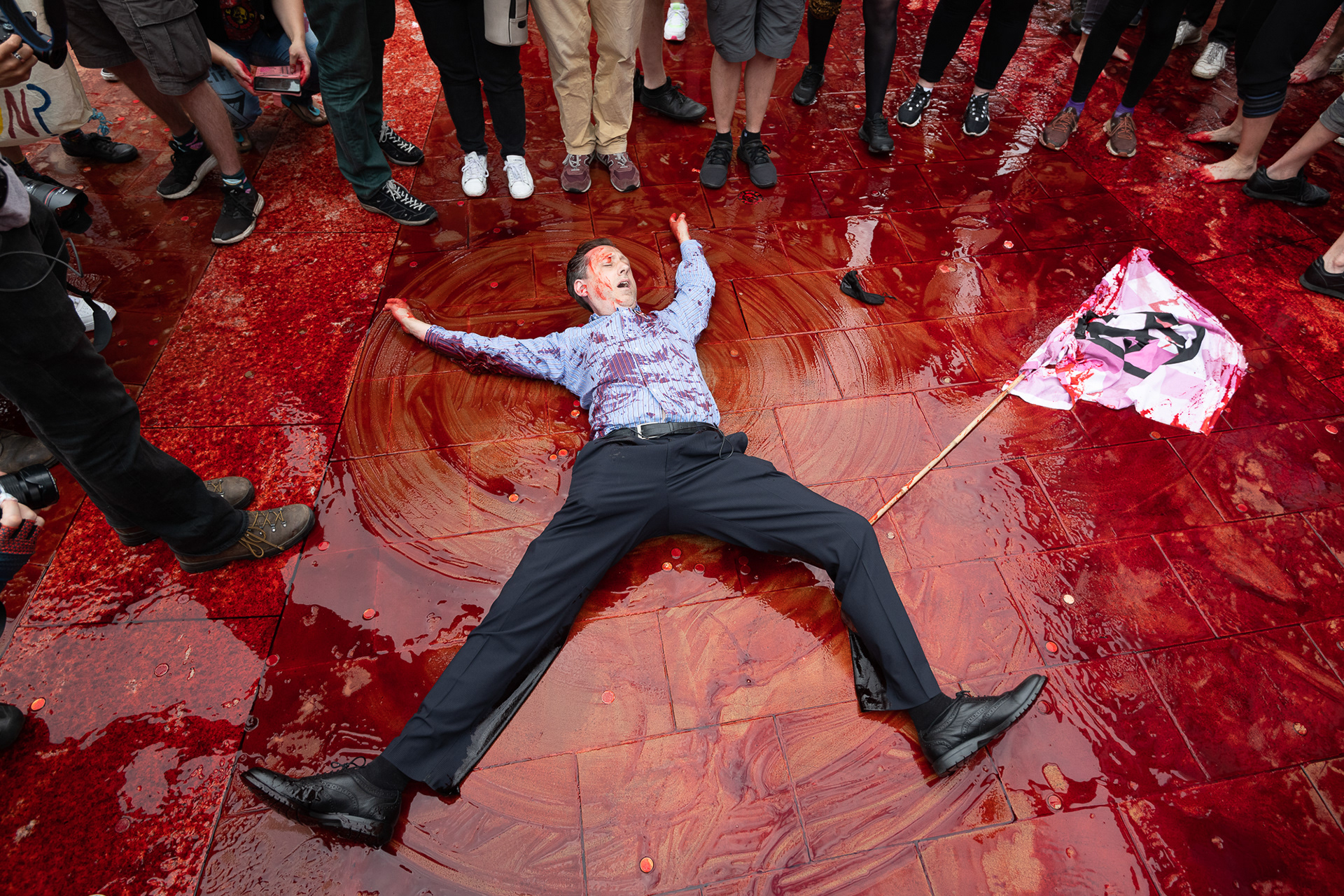 An Extinction Rebellion activist writhes in fake blood outside the London Stock Exchange during a climate protest calling for an end to fossil fuel funding. © Ron Fassbender