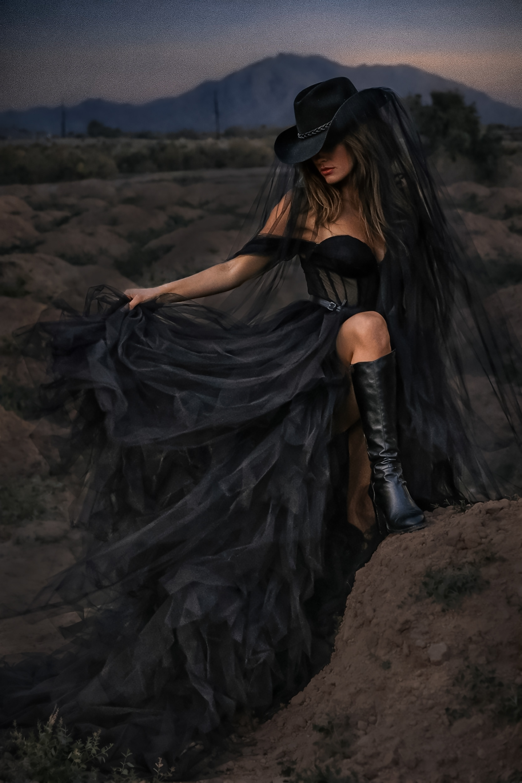 Fashion-inspired portrait of a woman in a black dress and cowboy hat in the desert.