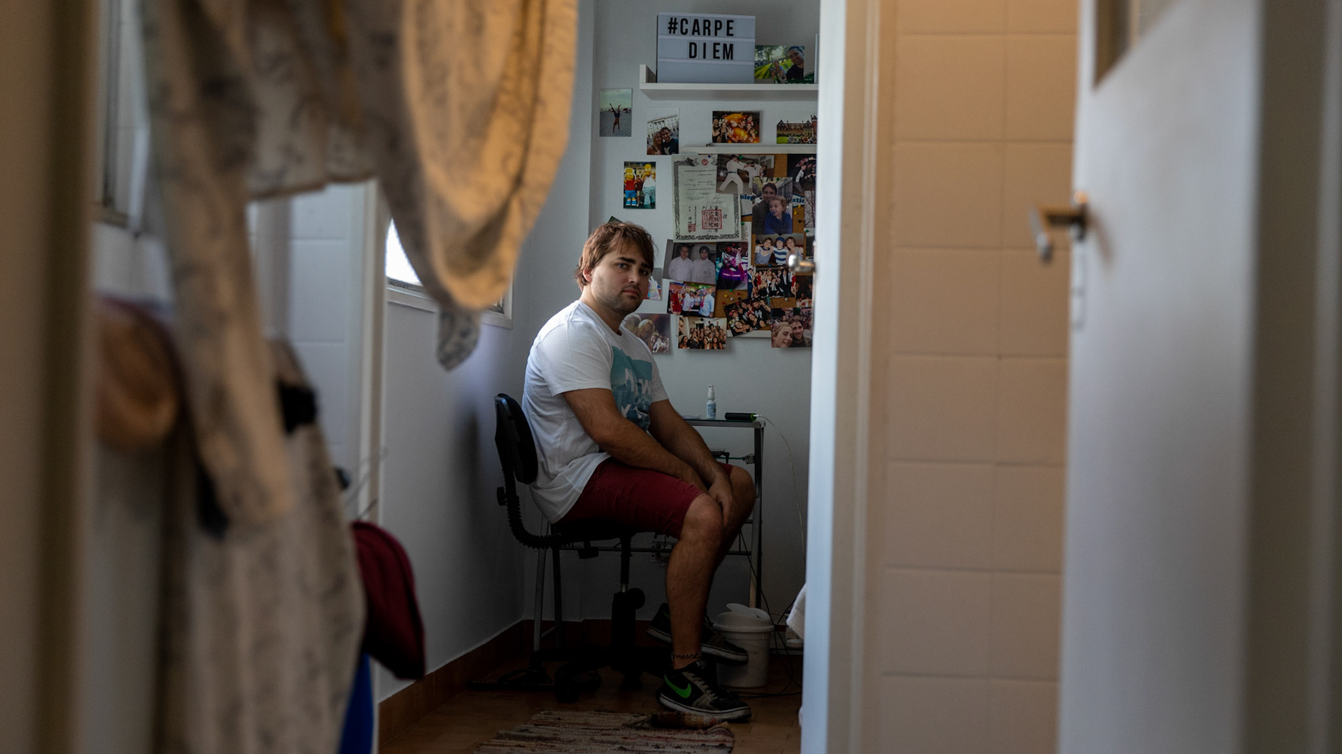 In this April 2, 2019, photo, Tomás Ruiz, 27, poses for a photo while sitting on a chair in his room at his mother's house in the City of Buenos Aires, Argentina. Before moving to Dublin, Ireland in search of work.