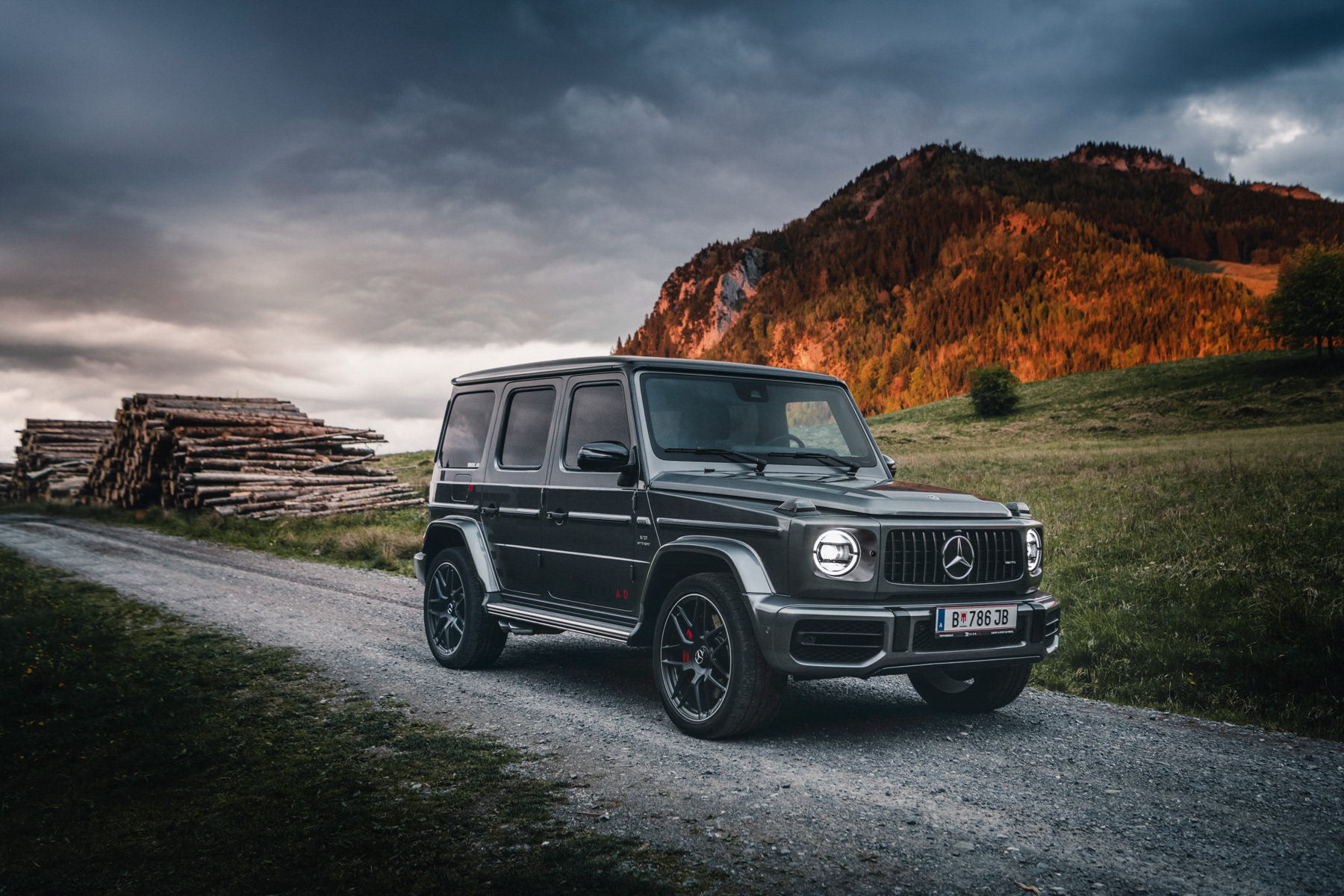 Auto Mercedes G Klasse steht vor dramatischem Hintergrund mit Bergen und Wolken auf Landweg