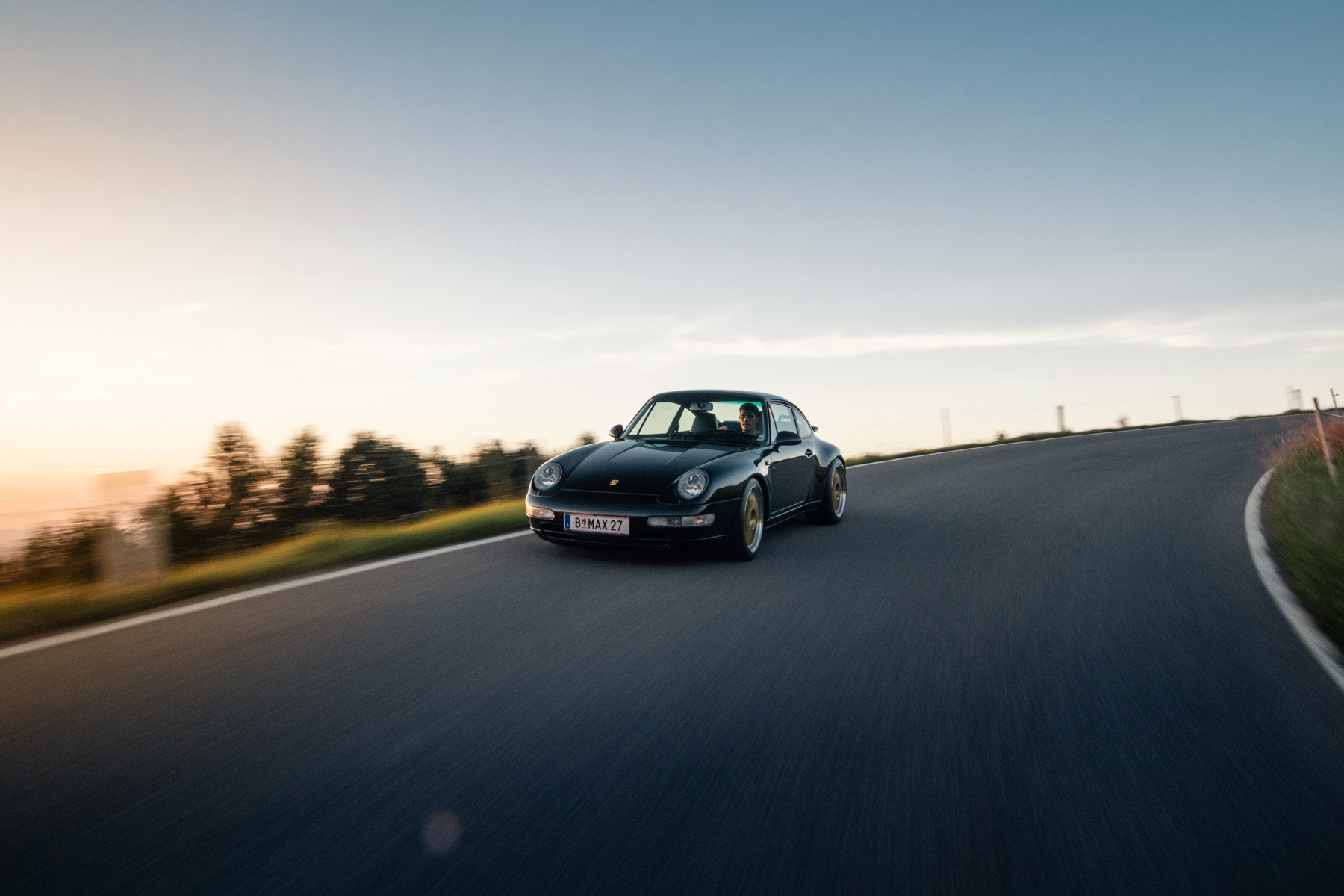 Auto Porsche während der Fahrt in Kurve bei Sonnenuntergang