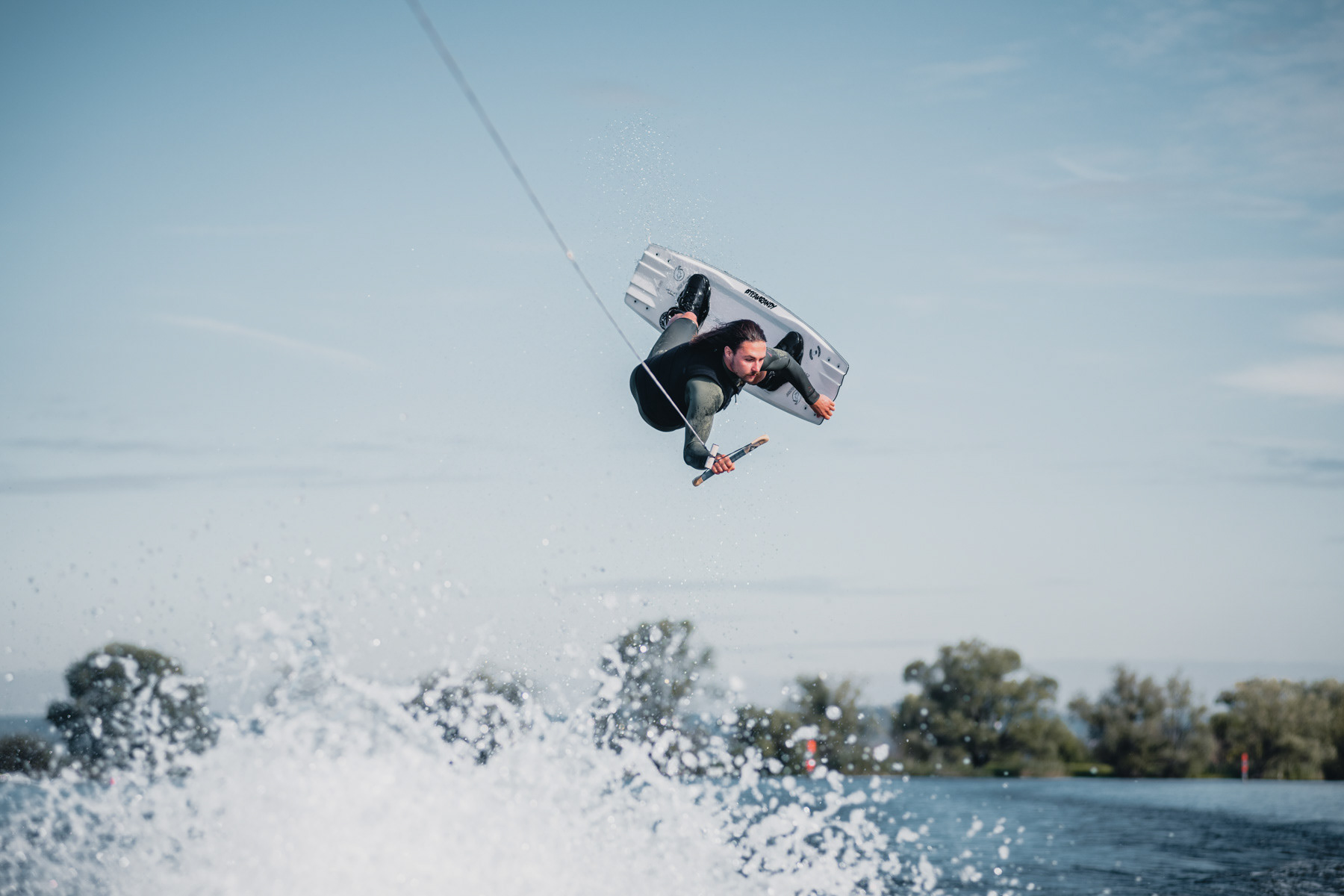 Sportfotografie Wakeboarder in der Luft bei Sprung mit Trick im Wasser