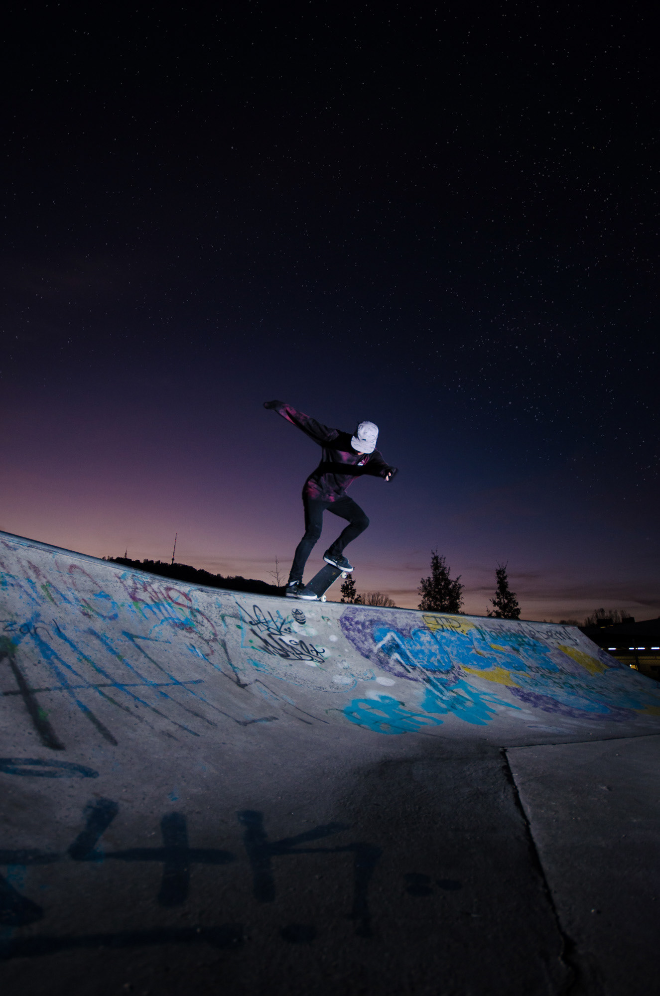 Skateboarder bei Nacht mit Trick in einer Quarterpipe