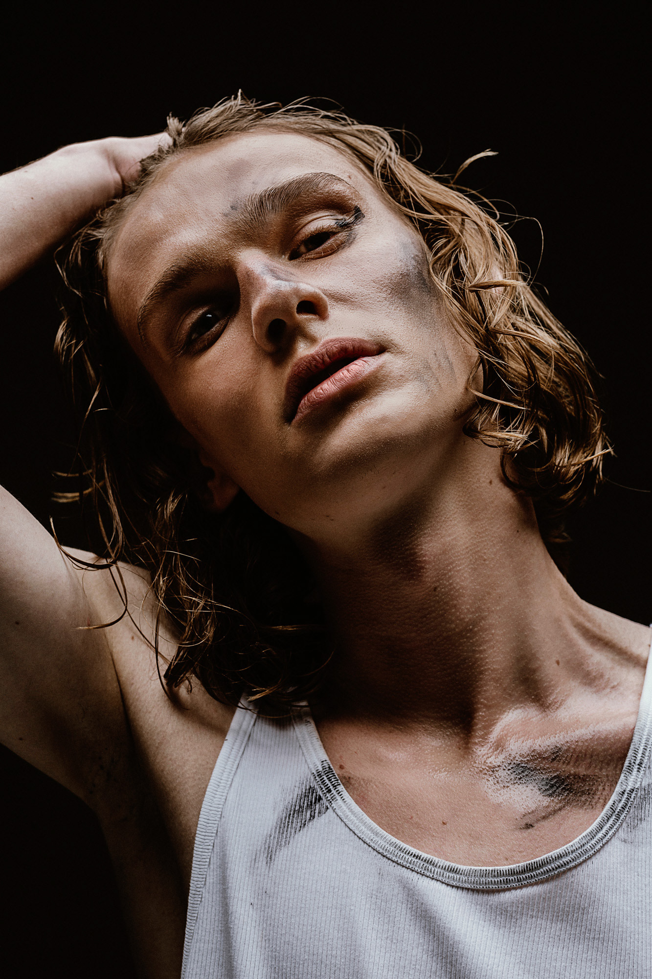 Portrait Mann mit Blick nach oben, langen blonden Haaren und Arm hinterm Kopf