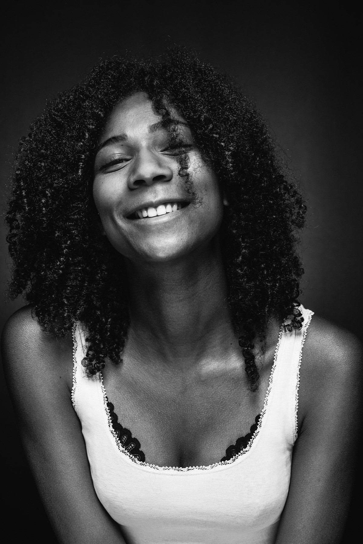 Schwarz Weiß Portrait Frau mit lockigen Haaren und breitem Lächeln