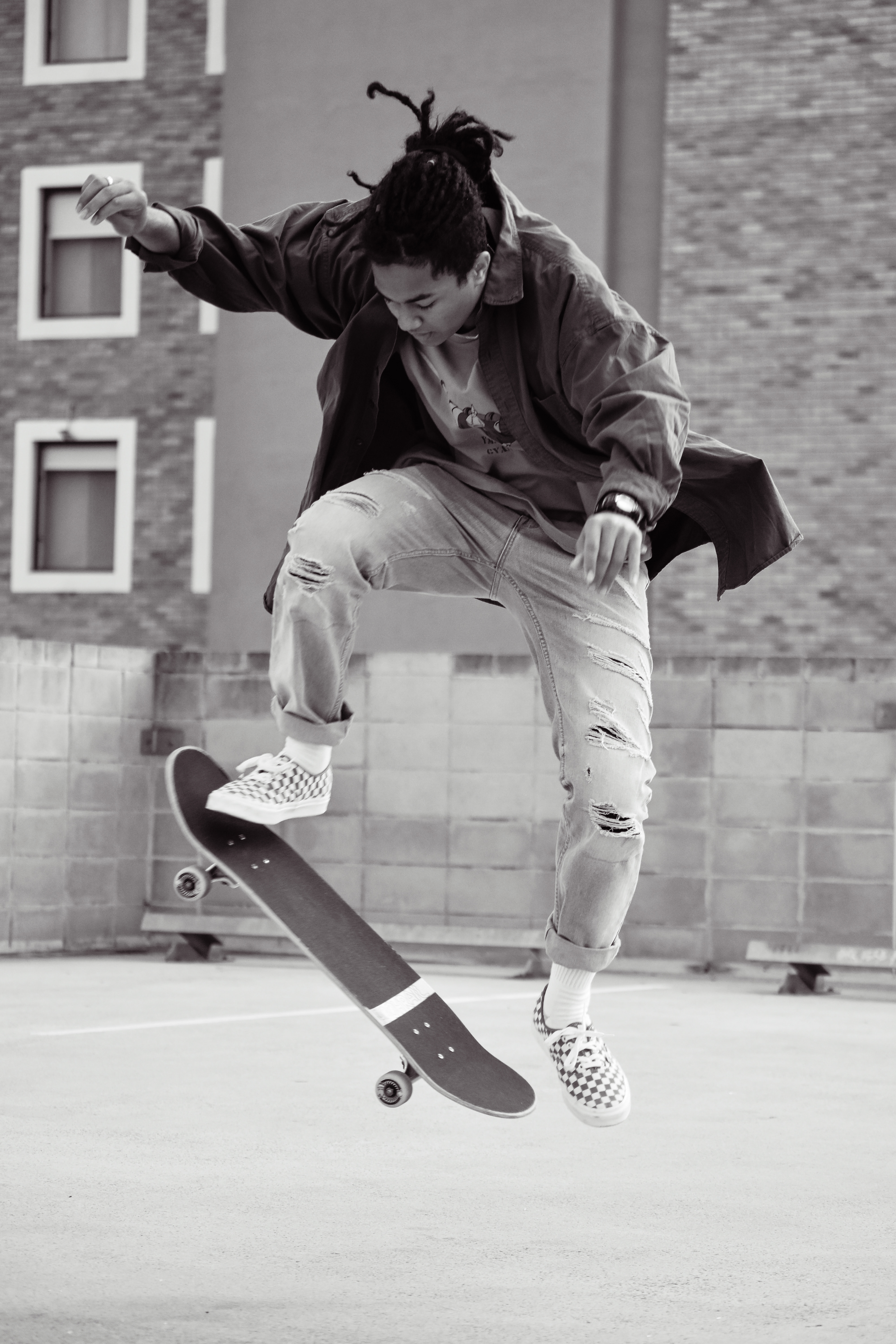 Black-and-white photo of skateboarder performing trick in urban setting.