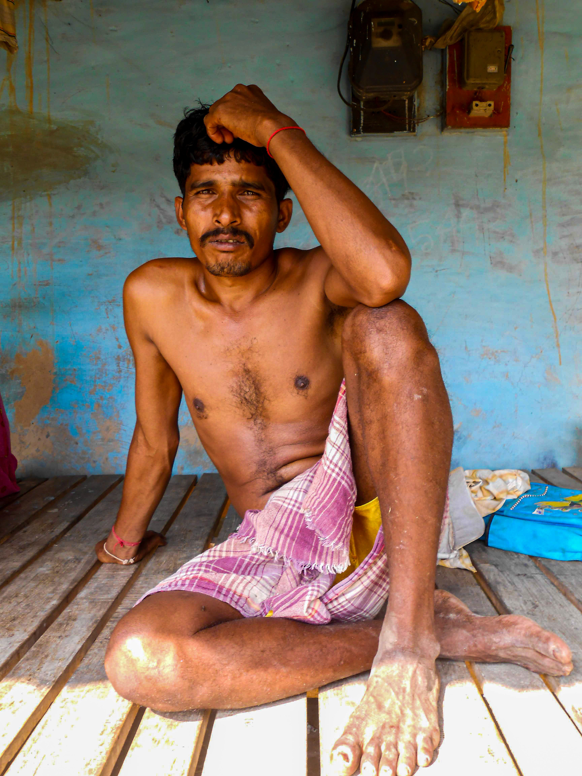 A sharecropper rests on a wooden bed in his front porch