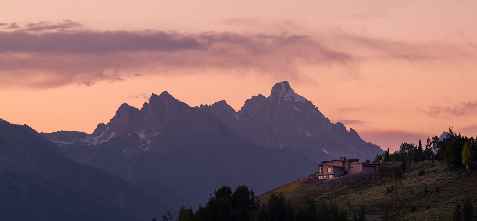 A compressed architectural image of a home built by New West Building company in front of the Teton Range in Jackson Hole Wyoming. Photograph taken at twilight by architectural photographer Aaron Kraft of Krafty Photos