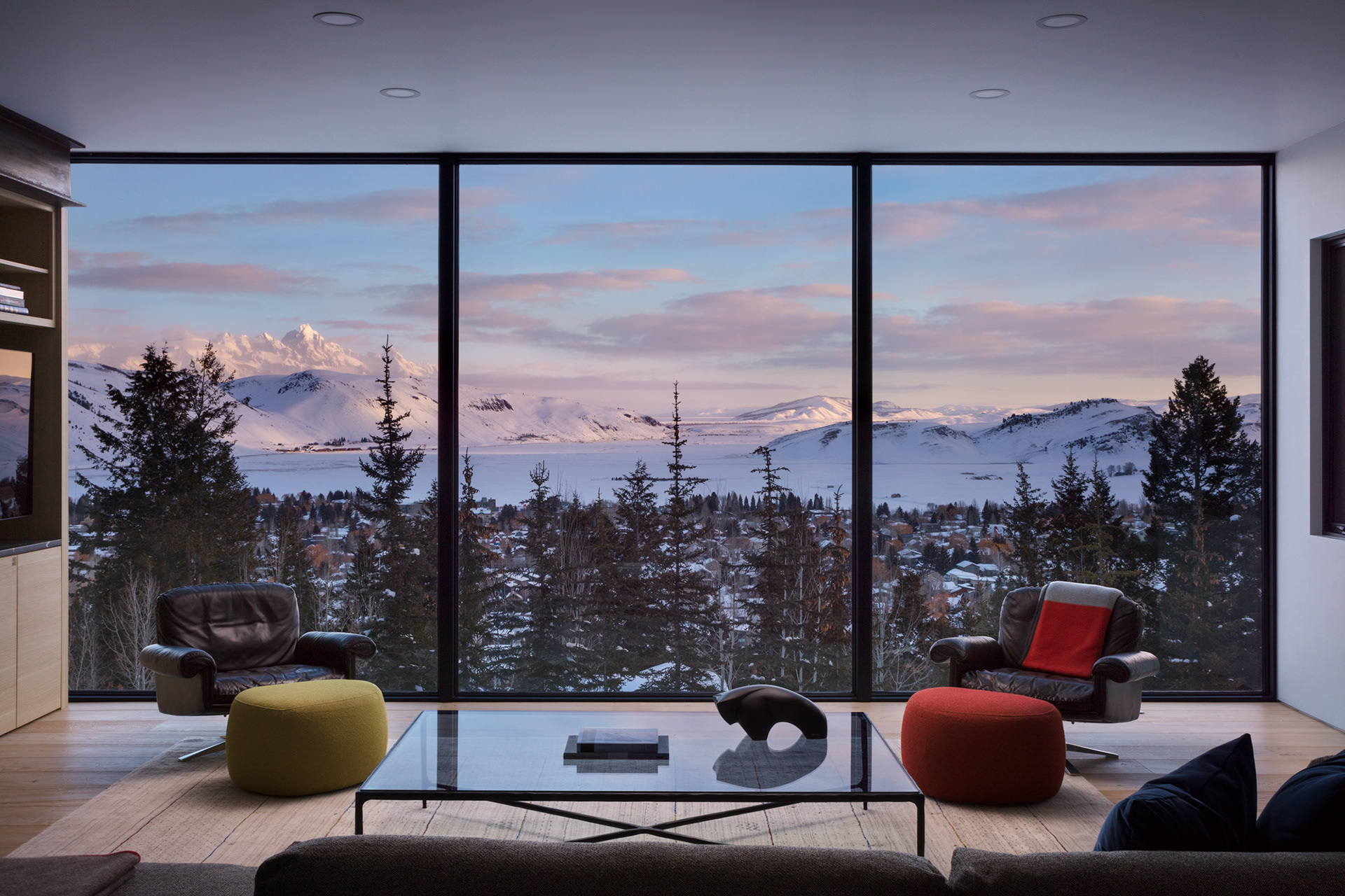 An interior design photograph of a modern home in Jackson hole Wyoming during the winter season. Sunrise on the Teton Range can be seen through the windows. Photograph by interior design photographer Aaron Kraft of Krafty Photos