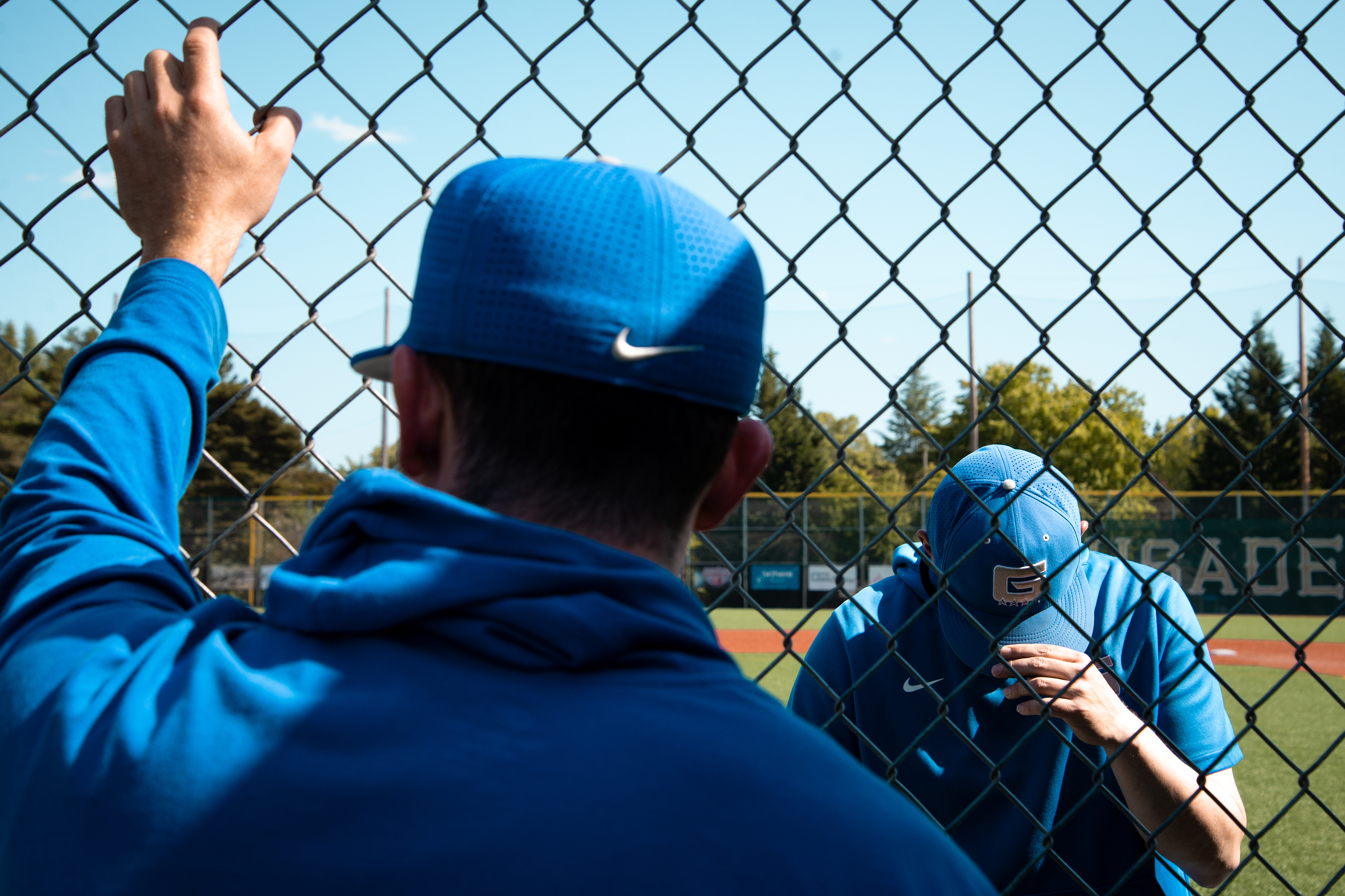 Two Grant baseball coaches watch warmups before semifinals