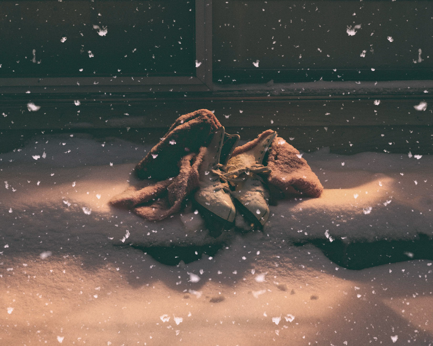 A young girls skates sit outside after a skate on the frozen pond.