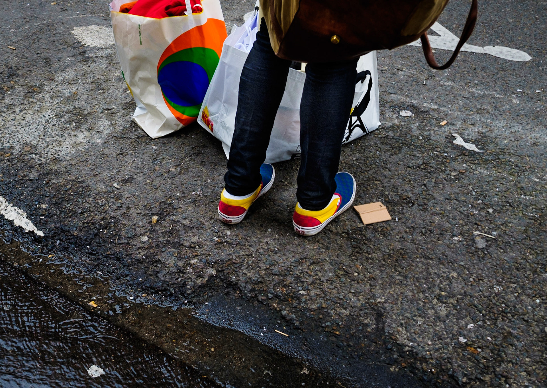 Mann mit bunten Schuhen und passender Tüte wartet am Straßenrand, Rochechouart, 9. Arrondissement, Paris, Frankreich
