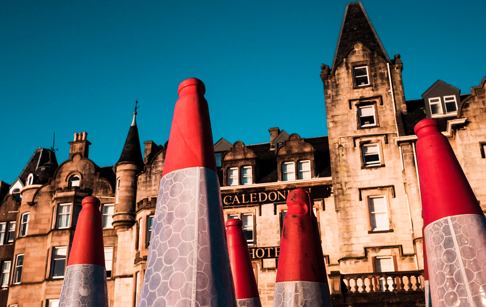 Traffic cones in the foreground match the shape of the roof of the building in the background, Oban, Scotland (United Kingdom 2016).