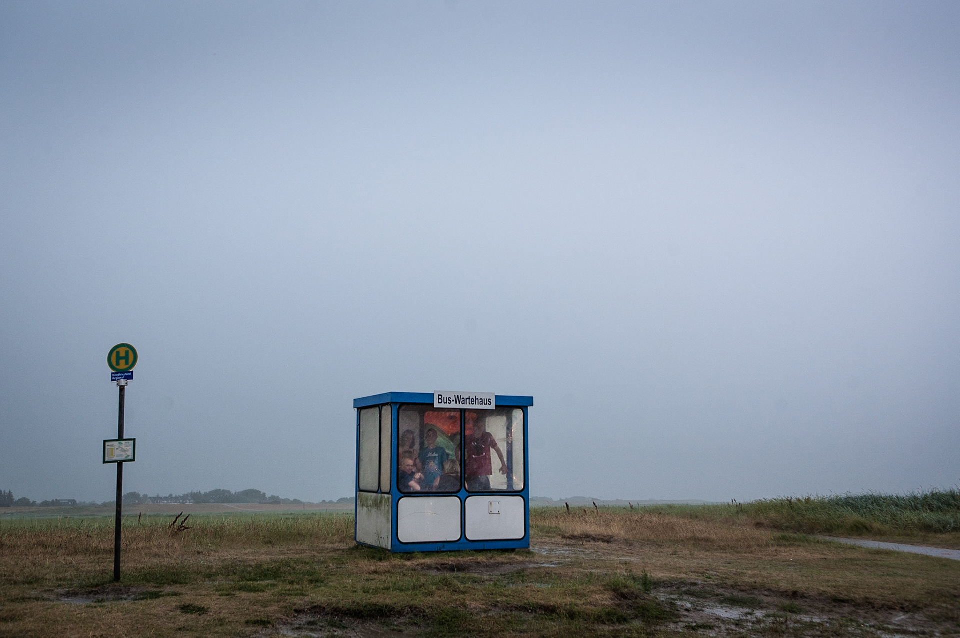 People waiting in a bus shelter for the ongoing rain to stop in St Peter-Ording (Germany 2013).
