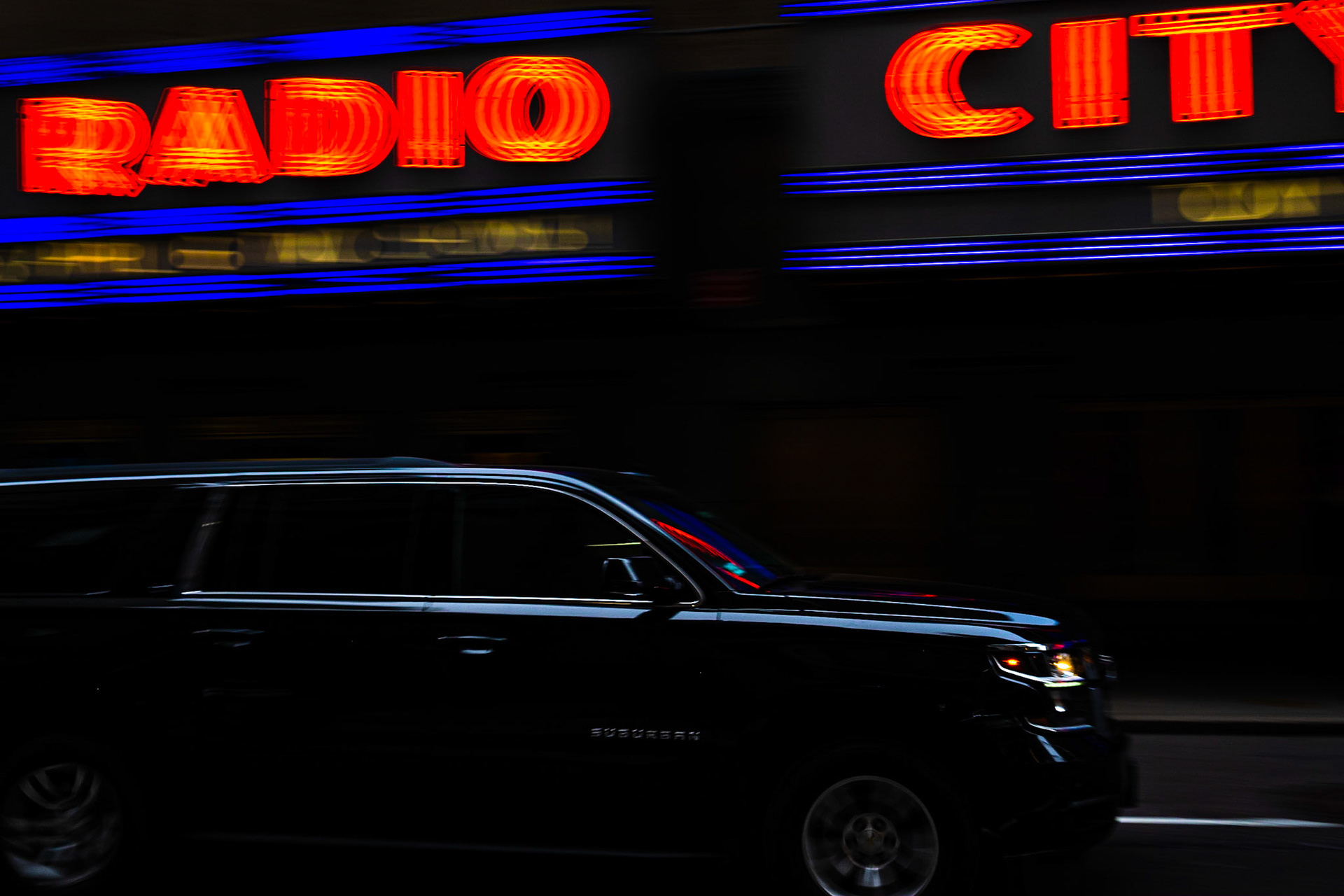 Car moving in front of neon advertising sign of Radio City Music Hall, Manhattan, New York City, USA