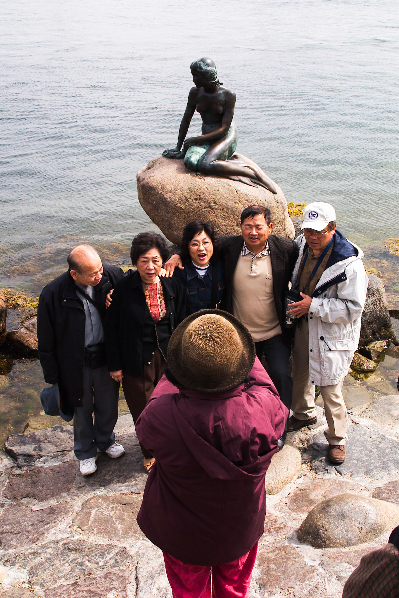 Eine Gruppe asiatischer Touristen lässt sich in Kopenhagen vor der Kleinen Meerjungfrau fotografieren.