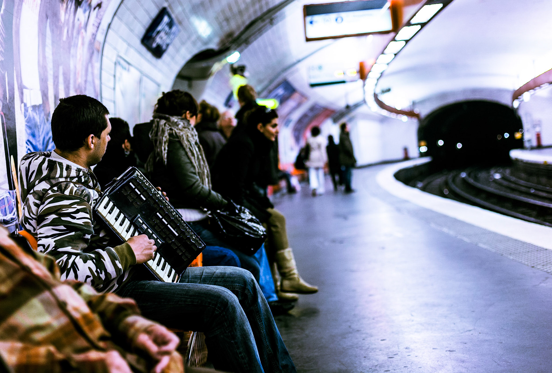 In der Pariser Metro-Station Pigalle sitzt ein Akkordenist auf der Wartebank.