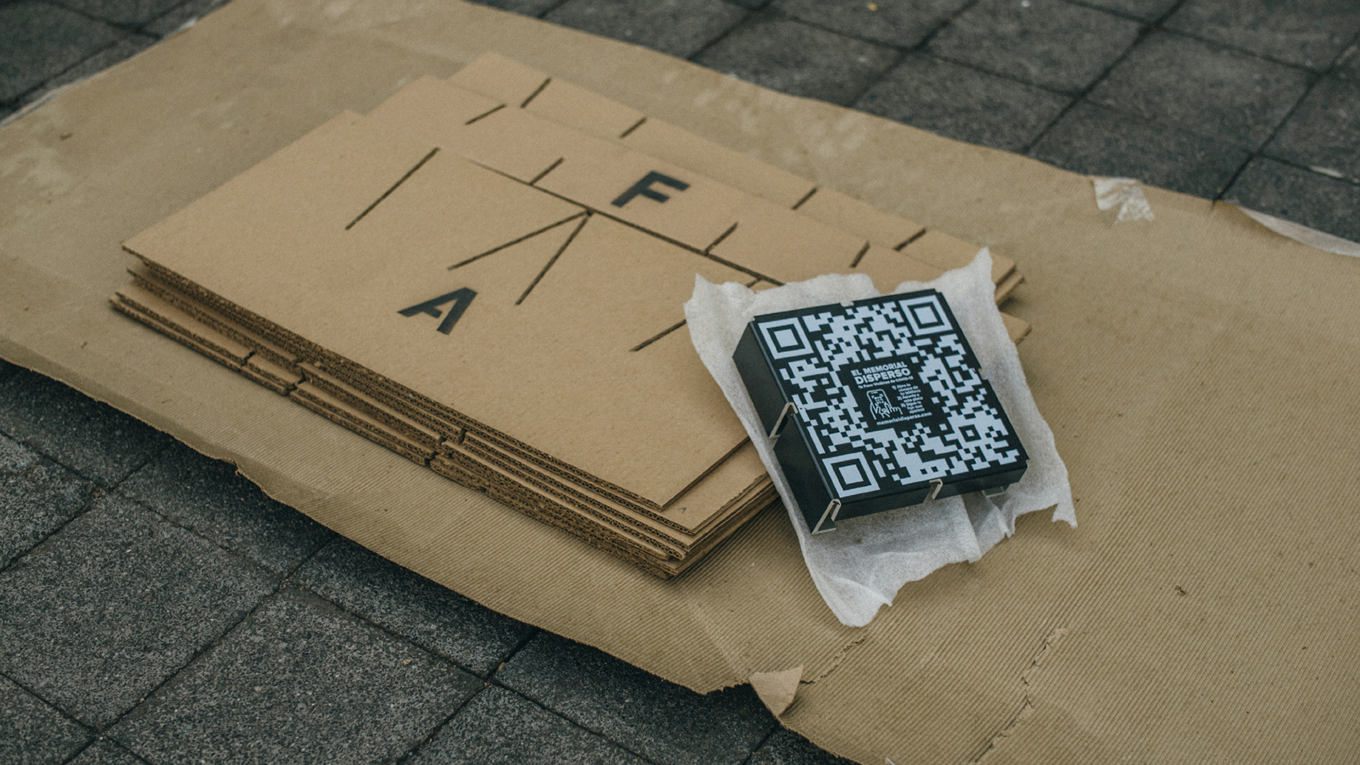 2 - Each Dispersed Memorial Kit contains cardboard pieces, a plaque with a QR code, instructions, and concrete pigment.