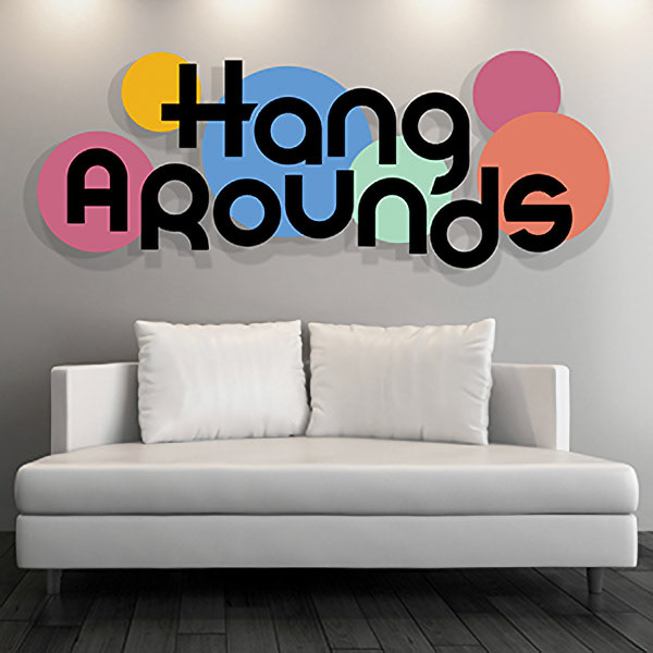 A sleek, modern white loveseat sits on top of a wooden floor in front of a white wall. Above the couch is the logo for HangArounds, which is fashioned to look like a layout of the actual product. The logo is a word mark which is in front of six circles, each a different size and color, and some overlapping each other.