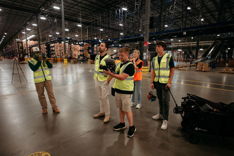 Dylan Smith of With A Twist Media filming an interview on a manufacturing floor in North Carolina