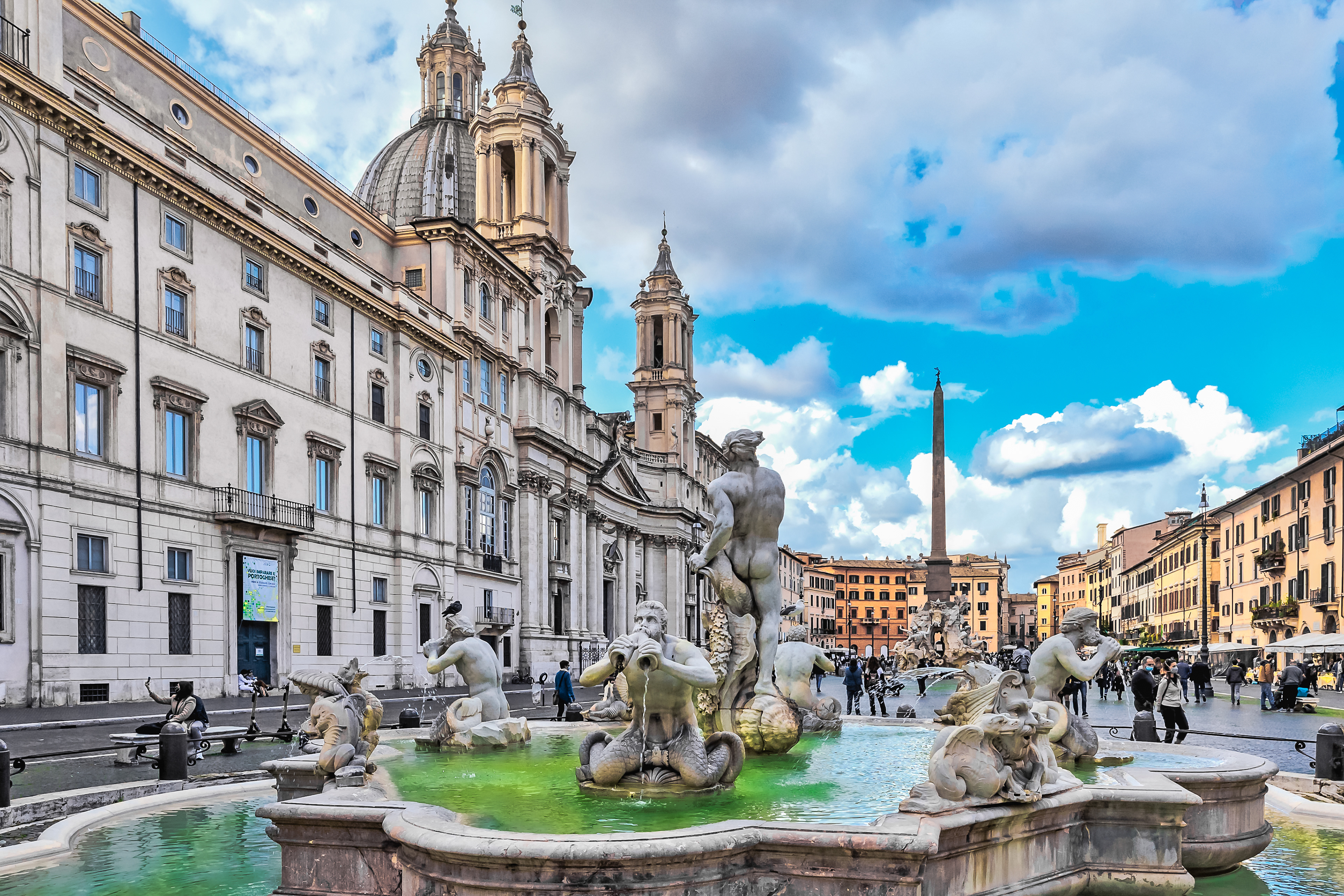 Piazza Navona mit dem Mohrenbrunnen mit Delfinskulptur und Tritonenfiguren und der Kirche Sant'Agnese in Agone