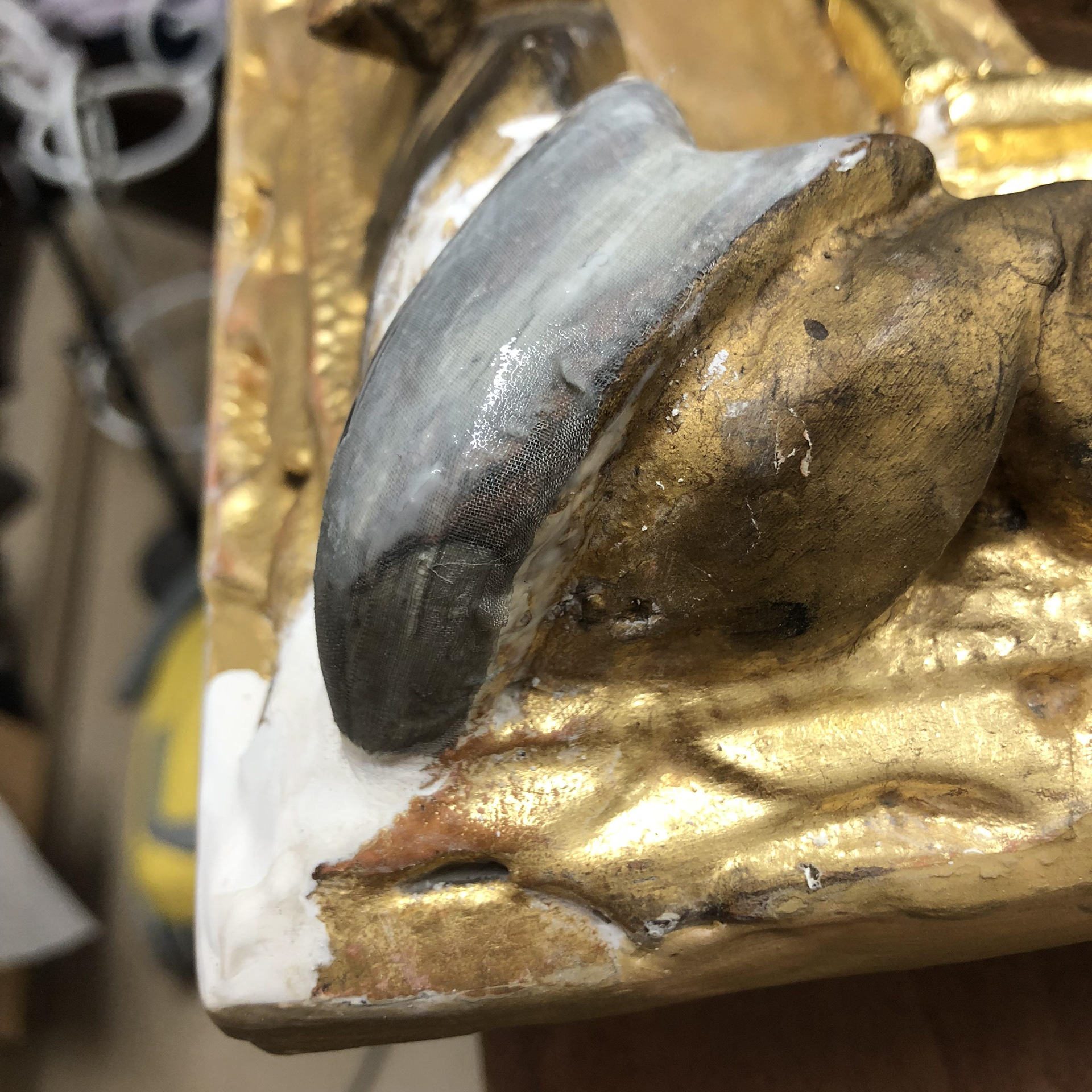 silk fabric used to strengthen the corners, then painted over with gesso and gilded.