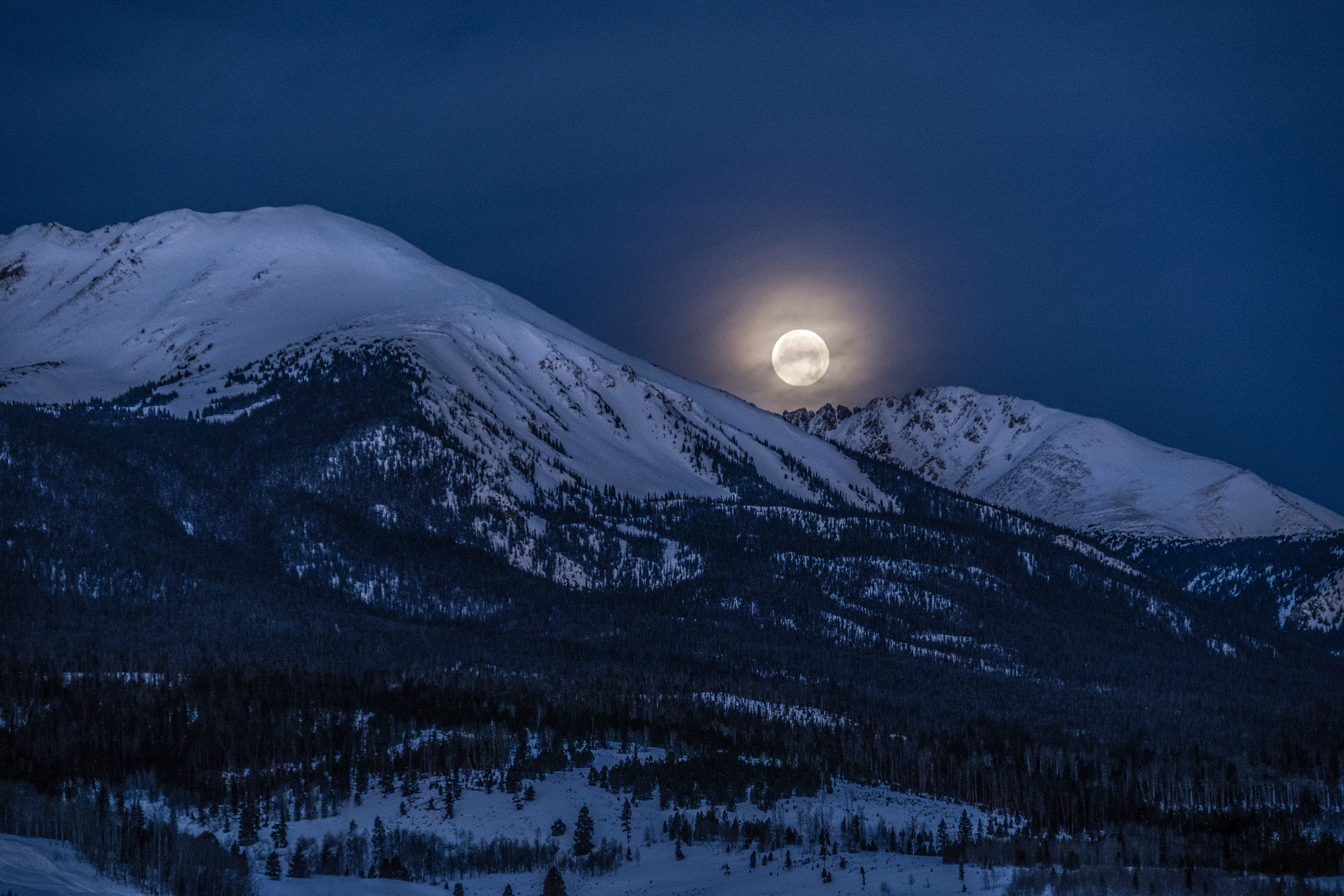 moon nestled between two mountain peaks at night