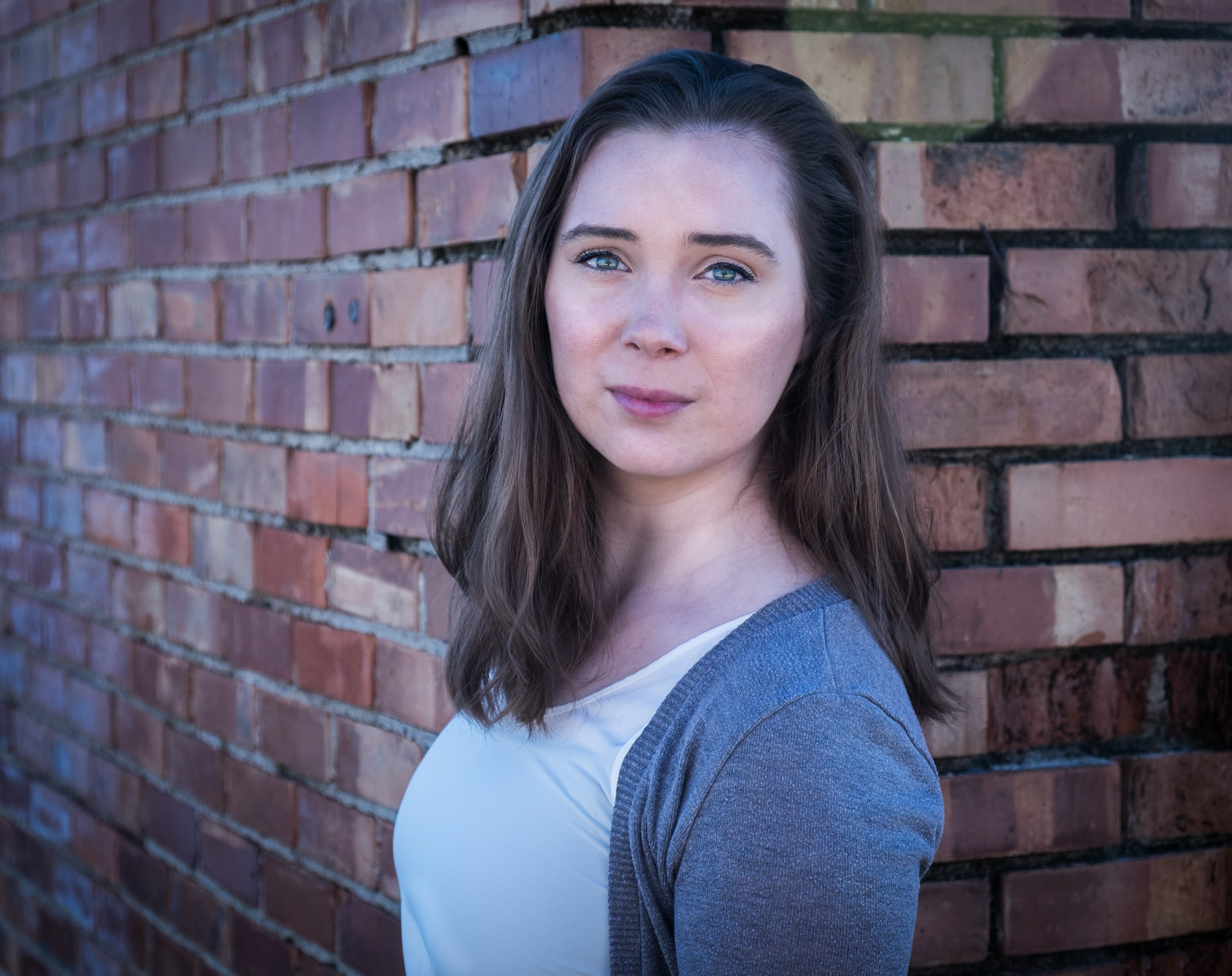 woman headshot posing by brick wall