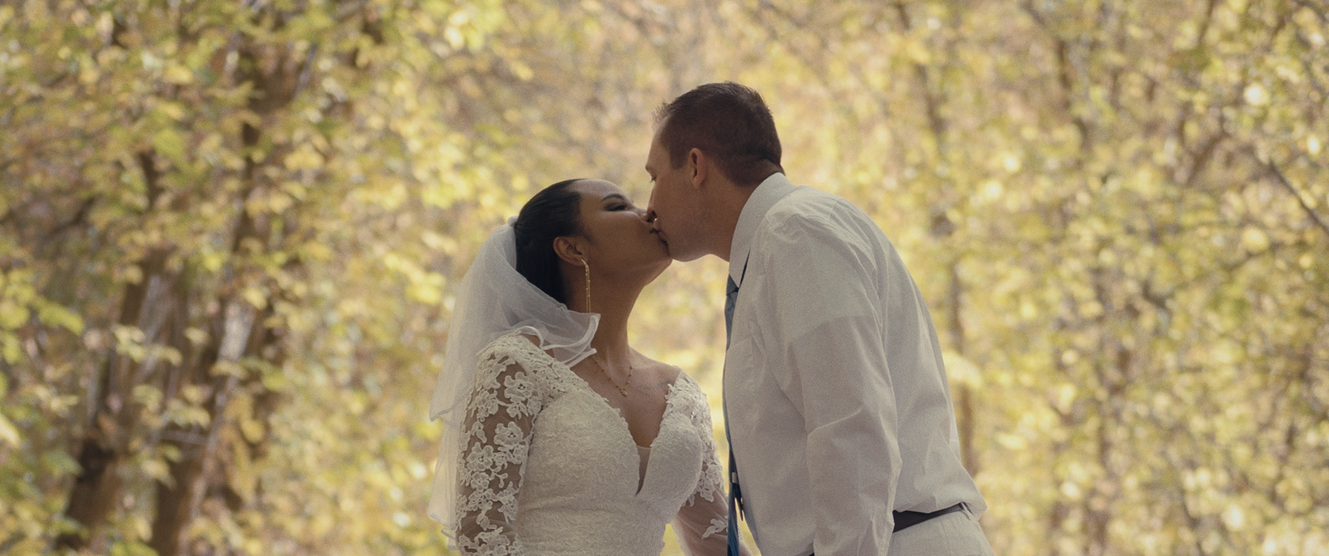 Bride and groom kissing at the end of their ceremony surrounded by autumn leaves in Pocatello, Idaho.