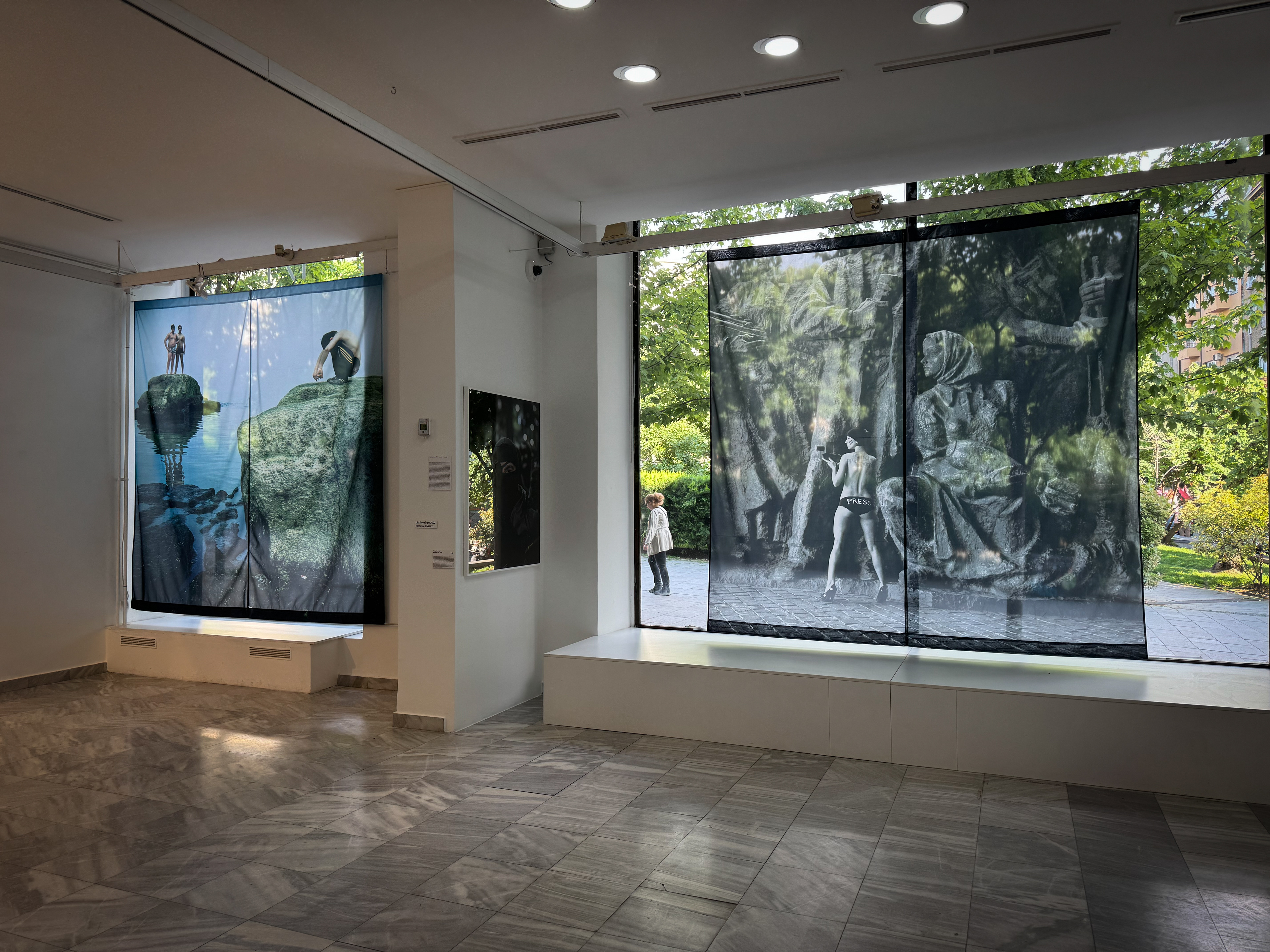 Kyiv, Ukraine, 2011:  Tatiana Zacerkovna, a topless FEMEN activist, poses for a photo in front of the Soviet-era sculpture of workers and World War II heroes at the National Museum of the History of Ukraine in the Second World War. While taking this photo, I was arrested by a policeman guarding the park. At that time, Ukraine was rife with corruption, and police were trying to extract fines at every corner. I had always feared the day would come when I would need to pay a bribe but wouldn’t be able to do it. The thought of giving a bribe paralyzed me; it felt strange and awkward. As I photographed that semi-nude girl in a public park for my series on FEMEN, I was careful to ensure that no random passers-by were exposed to it. At some point, the policeman approached us and took us to a small kiosk, demanding our documents and addresses where we lived or were registered. Allegedly, an old lady had complained to him that we had offended her feelings. They intended to file this as an administrative offense and proceed with a court case. We played the roles of nice, naive girls who were genuinely sorry for what we had done and pleaded to be let go. The policeman almost released us a couple of times, but then something would click in his head, and he would start the process all over again. After about half an hour, I finally realized that he wanted me to pay him a bribe for our release. Unsure how to offer the money, an idea struck me: I asked him what he would think if I paid the old lady 30 euros as an apology for offending her feelings. I continued, noting the sparkle in his eyes as he agreed to my proposal. “Pensioners don’t have much money; she could use that to take her grandchild or husband to a restaurant…” He happily concurred, and a small theatrical scene unfolded. He took a letter I had written to the old lady and went outside. After a while, he returned, eager to tell me that the lady had happily accepted the 30 euros and forgiven me. He let us go, thinking he had outsmarted us.