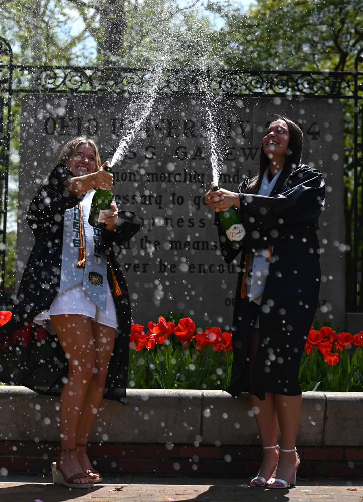 Aubrey Rea, left, and Izzi Boyd, right, shake champagne as they pose for senior photos on the College Green at Ohio University in Athens, Ohio, on Saturday, April 27, 2024.