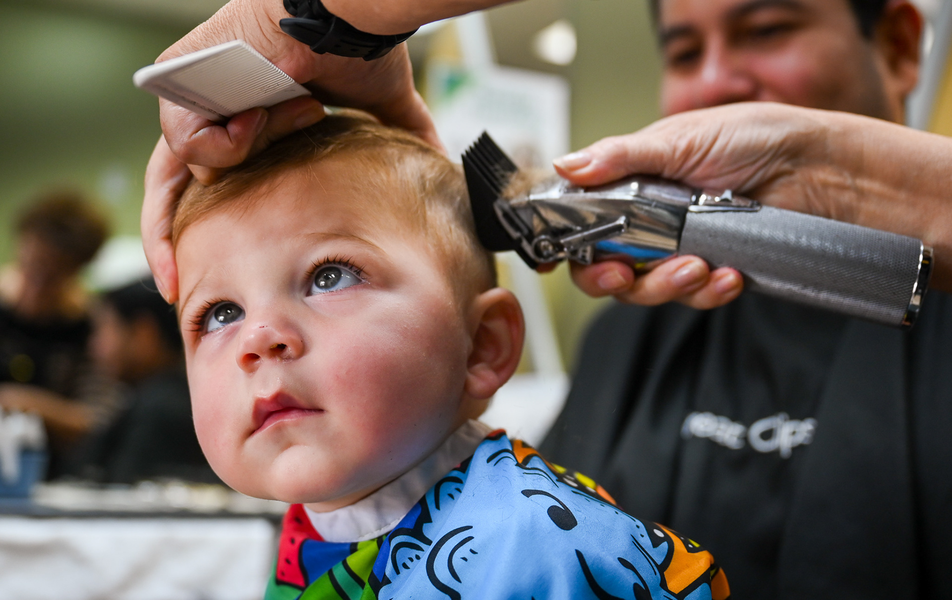 Noah P. receives a haircut while sitting on his father’s lap at Great Clips in Atlanta, Ga., on Nov. 15, 2025. Noah, 1, gets his second haircut from stylist Zila Yupoe as his father holds him for support. “He did so much better than last time,” Zila said. “He’s a good boy.”