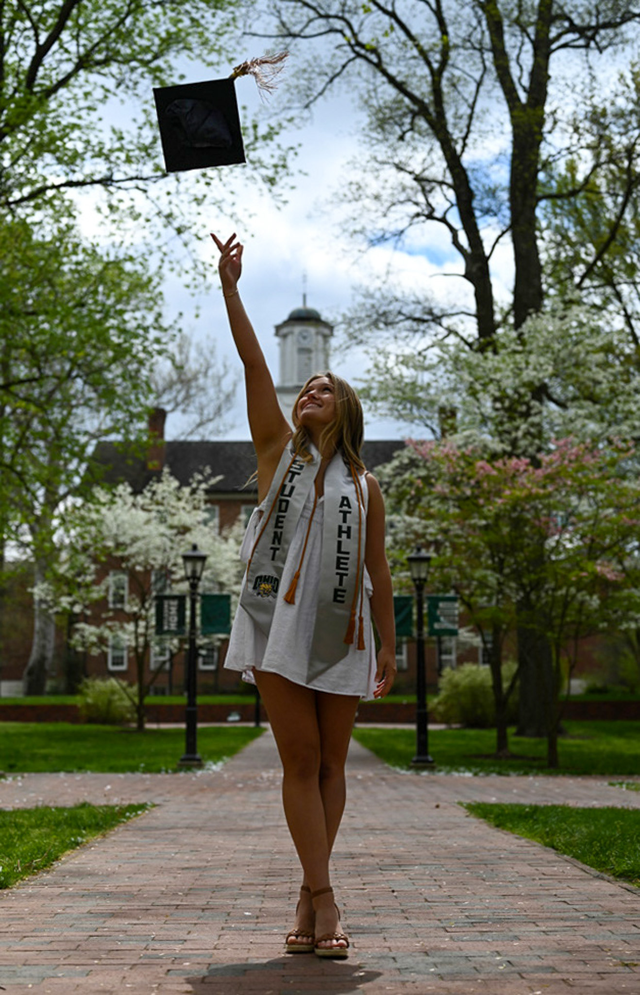 Aubrey Rea tosses her grad cap for senior photos on the College Green at Ohio University in Athens, Ohio, on Sunday, April 21, 2024.