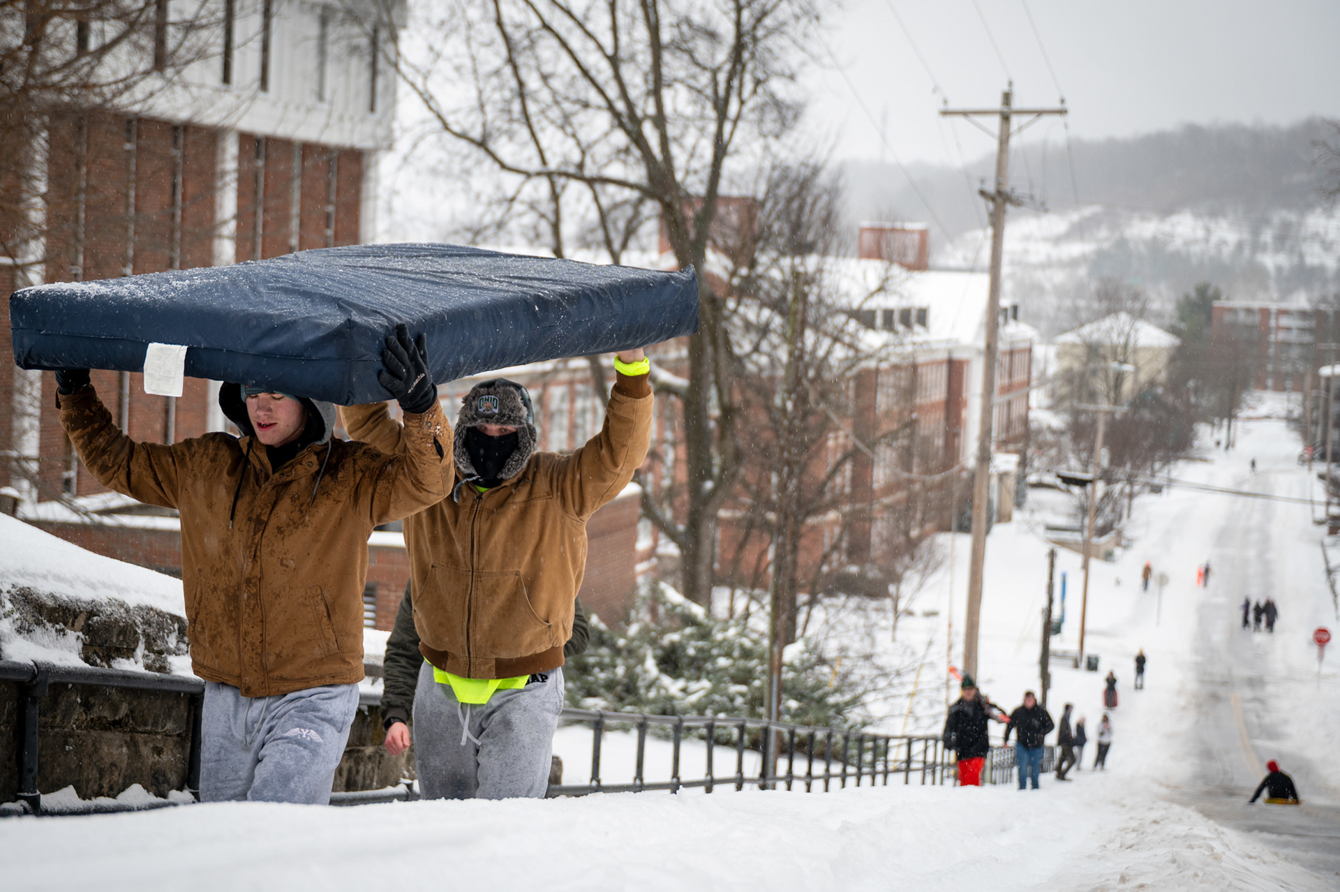 Ohio University freshmen Andrew Miller and Couper Blind haul a dorm mattress up Jeff Hill during a Level 3 snow emergency in Athens County on Sunday, Jan. 25, 2026. Large crowds of students gathered on the hill to sled throughout the day. 