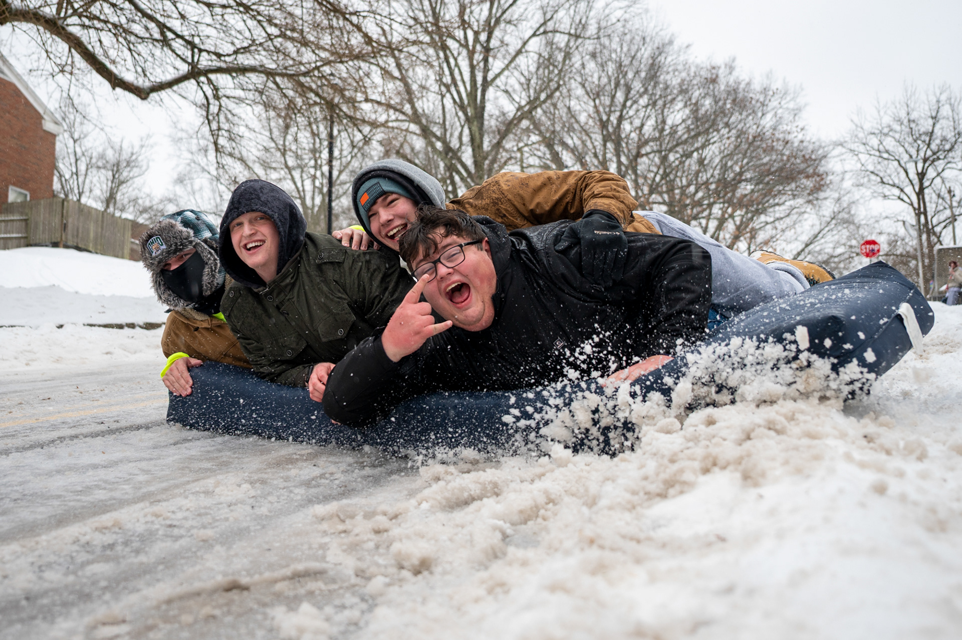 Couper Blind (left), Justin Nadiak, Andrew Miller, and Lucas Schalmo (right), college freshmen, ride a dorm mattress down Jeff Hill during a Level 3 snow emergency at Ohio University on Sunday, Jan. 25, 2026. After a neighbor moved out, the friends repurposed the spare mattress as a sled, taking turns riding it down the hill multiple times. Despite the extreme cold and slow-moving week caused by the storm, they saw it as a fun, adventurous way to make memories together. “This is the best time to make fools of ourselves and make memories we’ll tell for years,” Miller said.