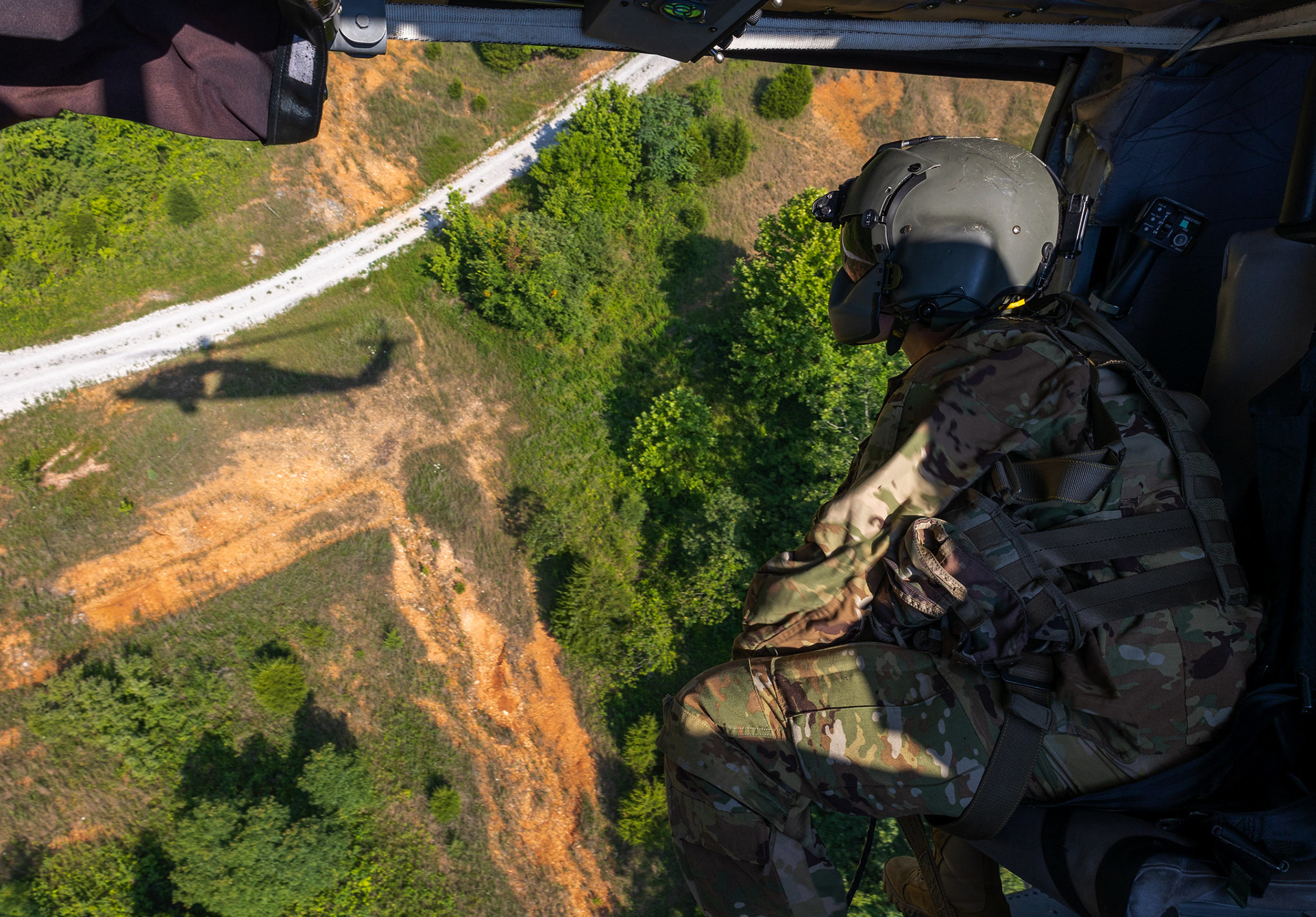 Spc. Tyler Eshelman, Fort Bliss, TX., 15 Tango Black Hawk Mechanic, gazes out the door while he performs a practice ground evacuation in a HH-60M “Mike” model Black Hawk helicopter on Fort Knox, KY., June 22, 2024. In medical evacuations, meticulous preparation through practice sessions ensures that personnel and ground teams are well-prepared to execute their roles efficiently during emergencies. |Photo Credit: Ayiana Andrella, Ohio University, CST Public Affairs Office