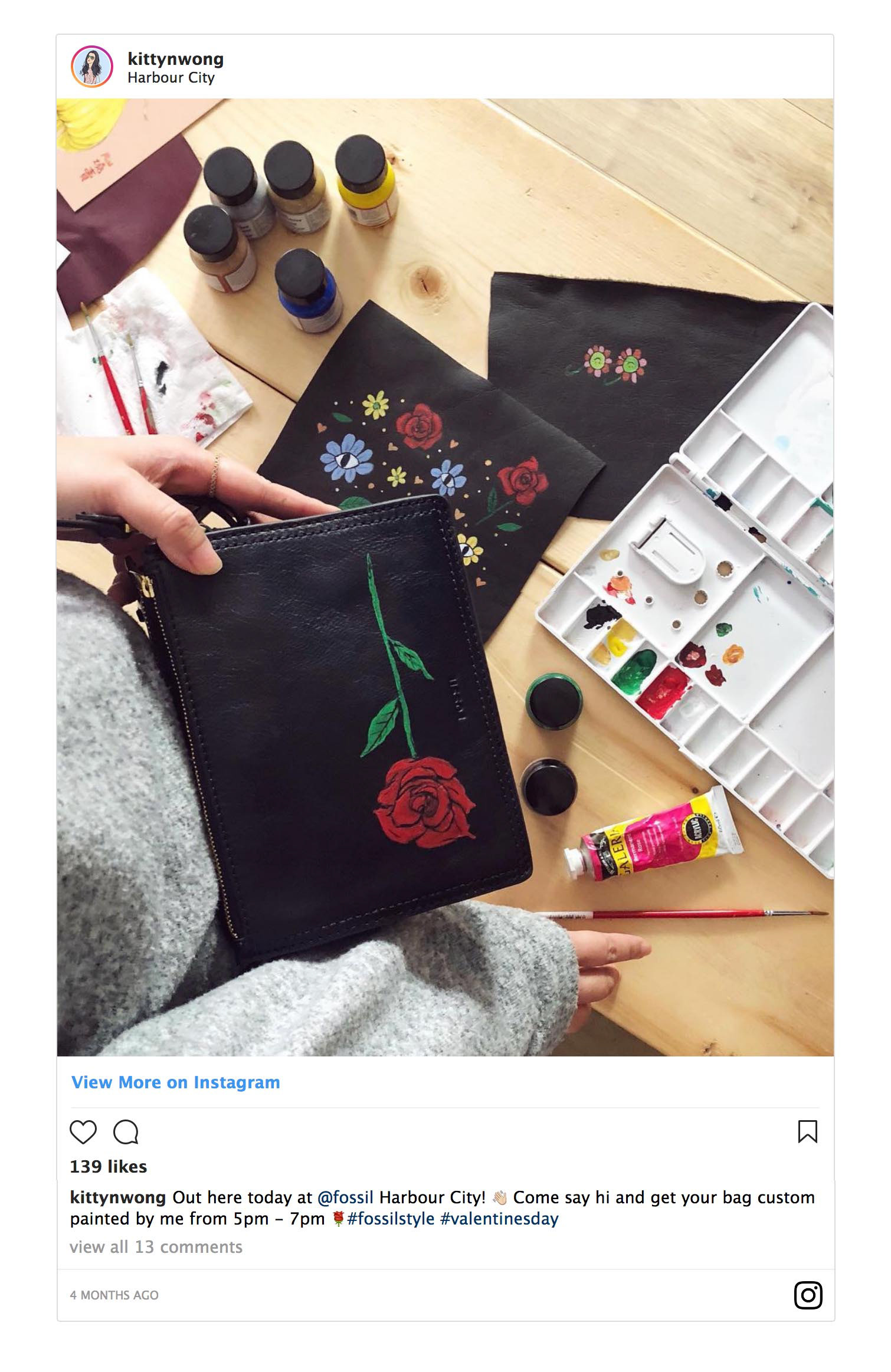 Instagram screenshot of art flatlay of red rose painted on black leather fossil cross body handbag