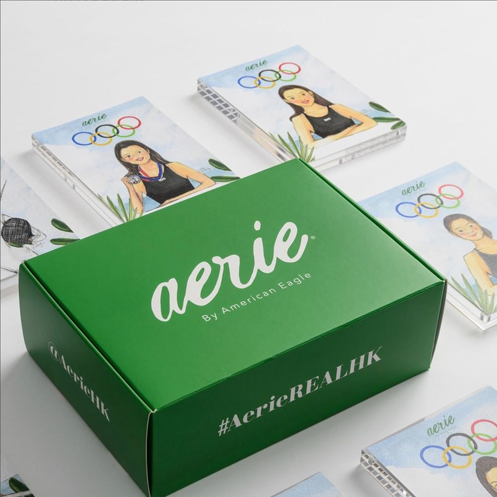 Green gift box that says "Aerie" next to painted portraits of Hong Kong Olympic woman athletes