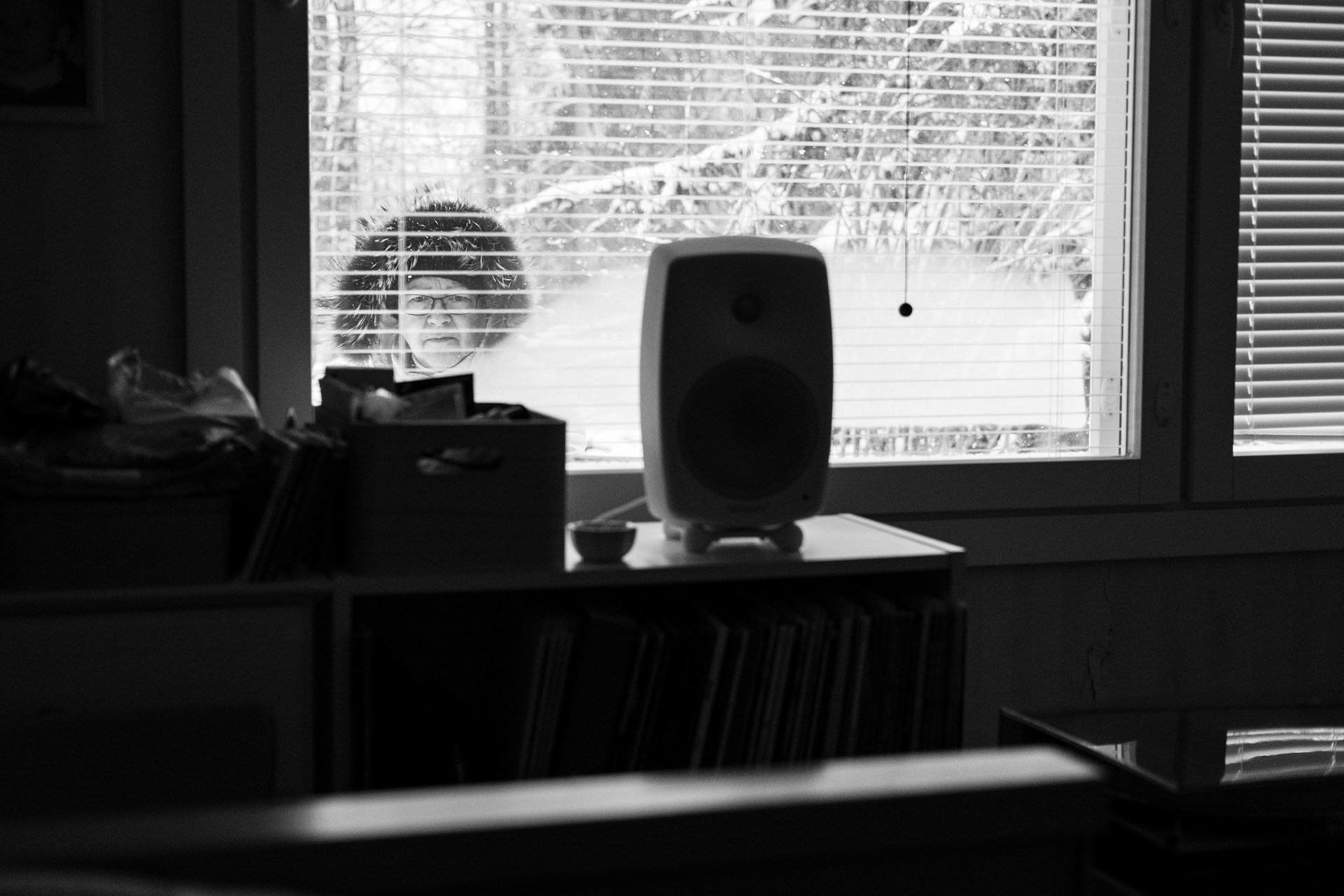 A black-and-white photograph taken from inside Niko’s room of his mother wiping off snow from the outside of the window.