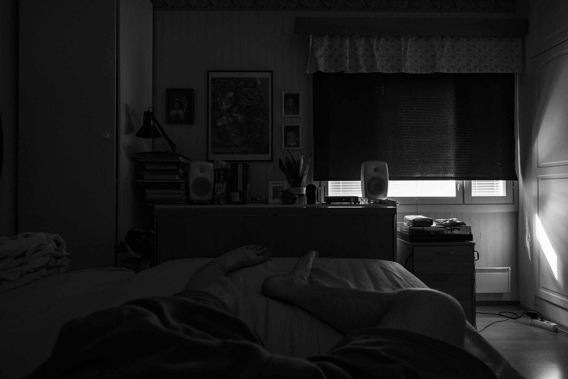 A black-and-white photo taken from Niko’s point of view while he lies on his bed. The blackout curtain almost fully covers the window.