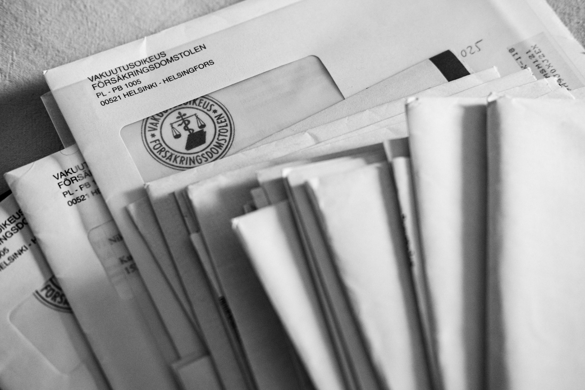 A black-and-white close up photograph of a pile of papers and envelopes.