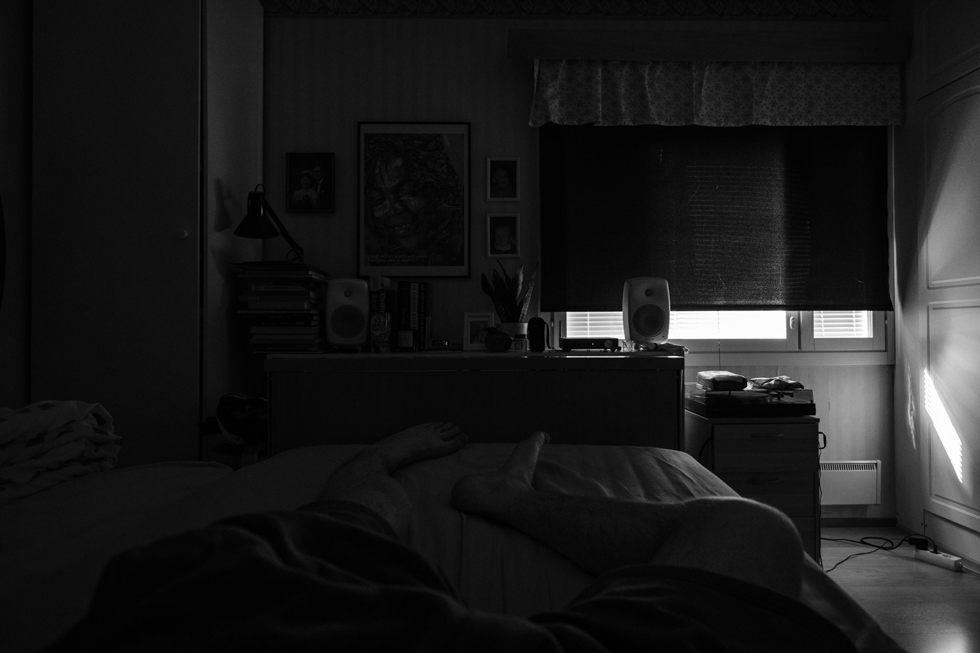 A black-and-white photo taken from Niko’s point of view while he lies on his bed. The blackout curtain almost fully covers the window.