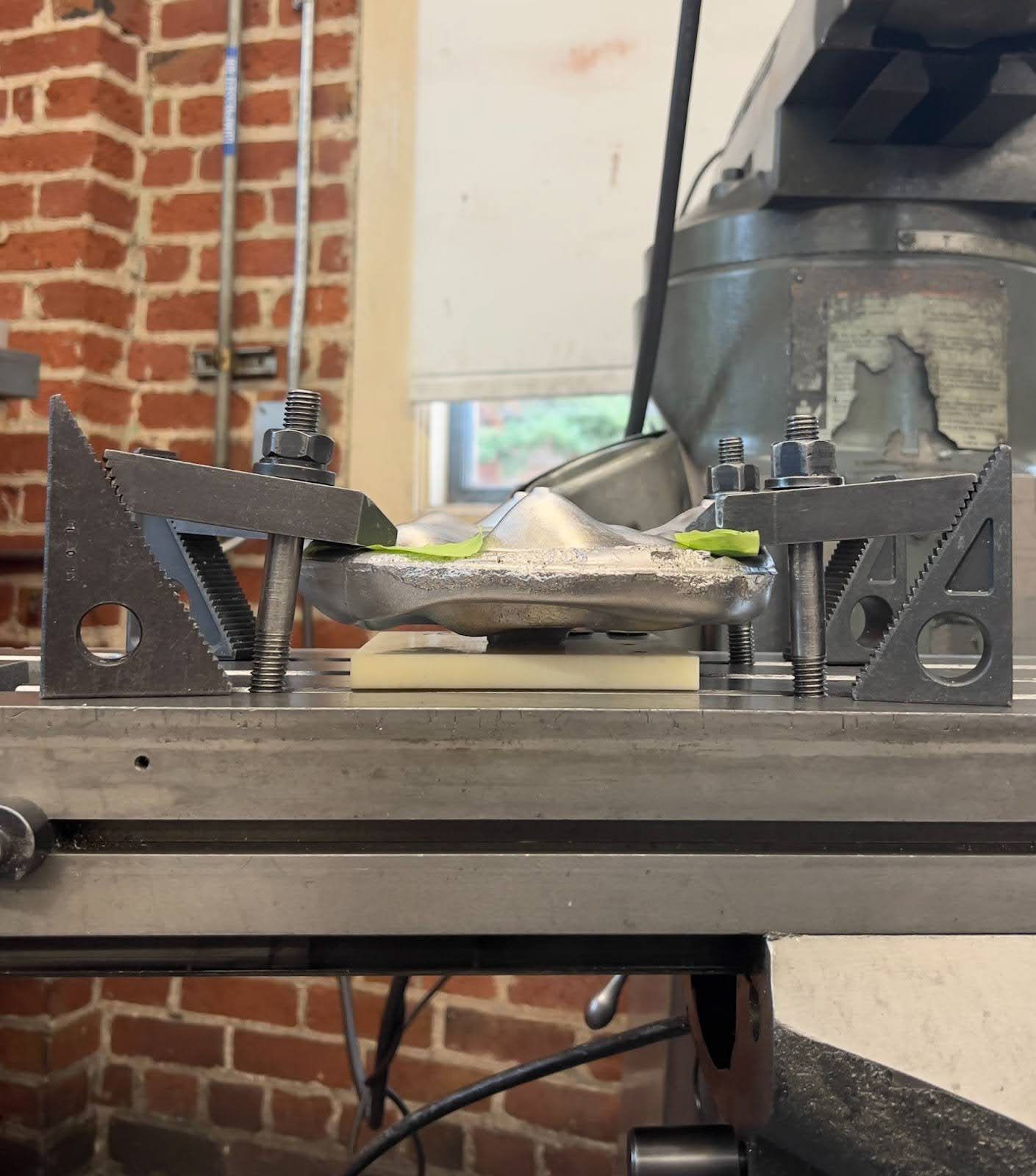 Fixturing one of the organic shapes onto the mill with strap clamps and sacrificial material underneath.