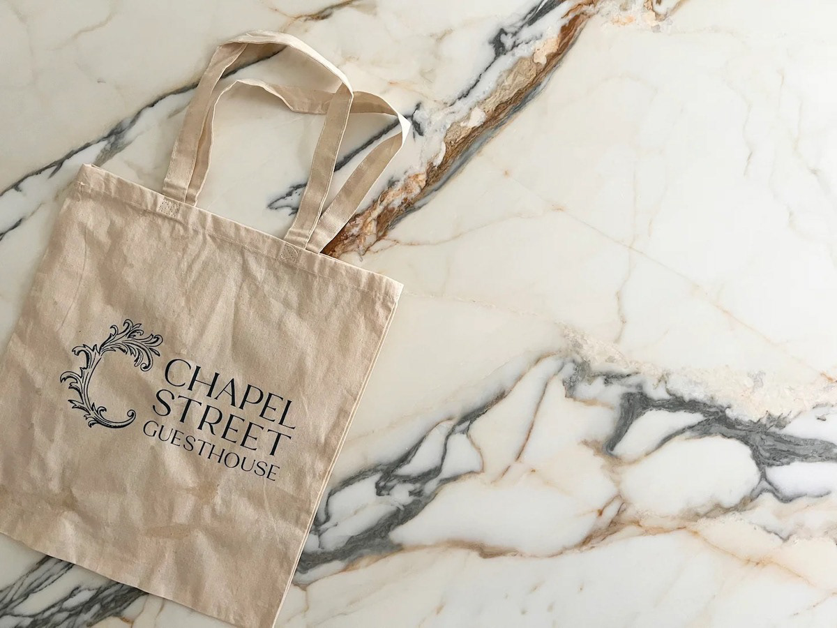 Tote bag with the Chapel Street Guesthouse logo on a marble countertop