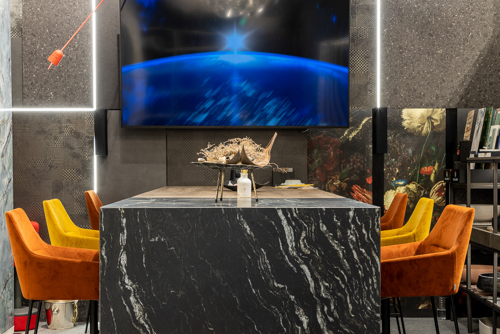 Masa cu venaturi albe si scaune portocalii si galbene, intre finisajele expuse in Arthitek Showroom.