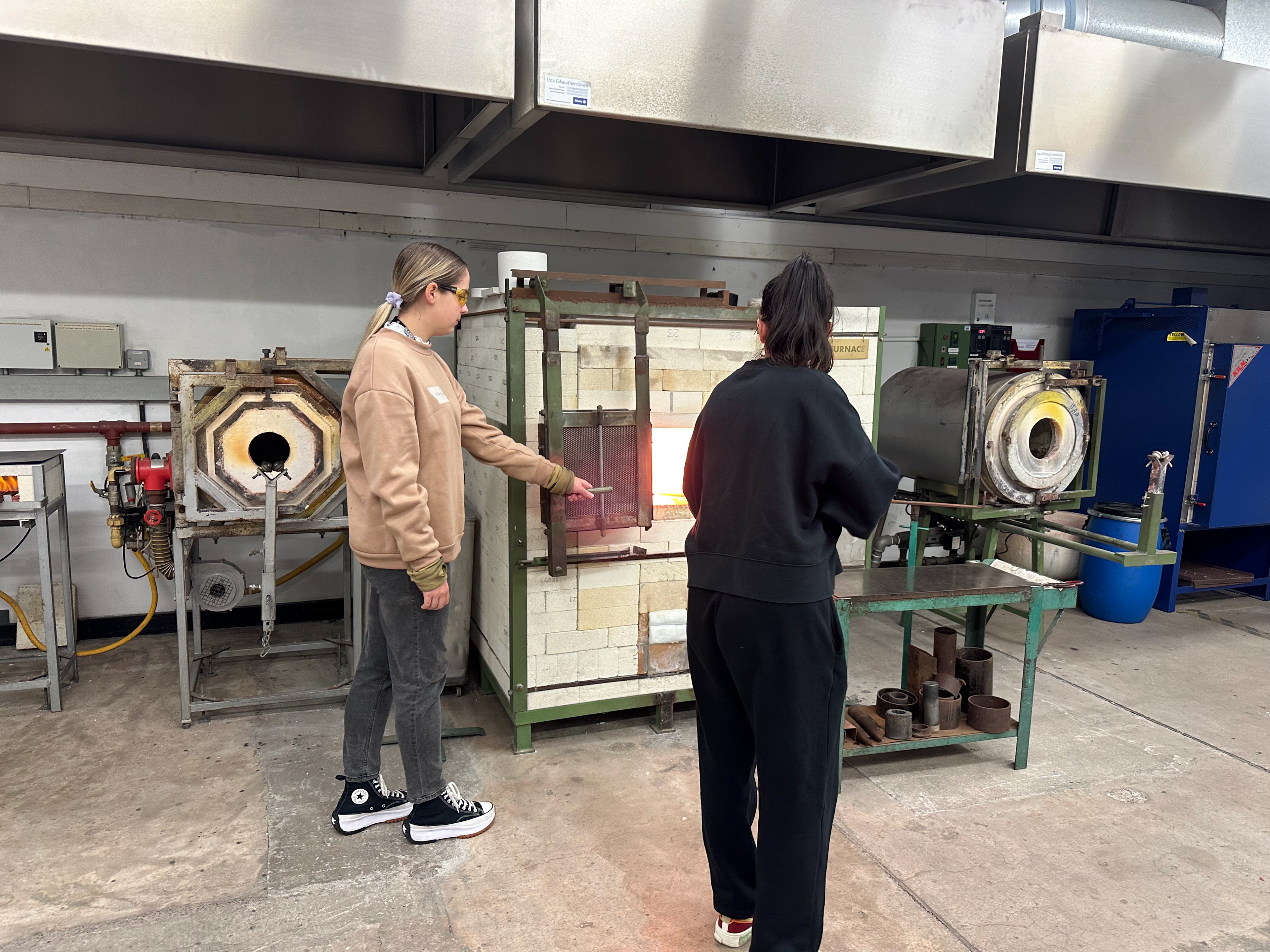 One person opens the furnace door whilst the other dips the pipe into the molten glass whilst turning.