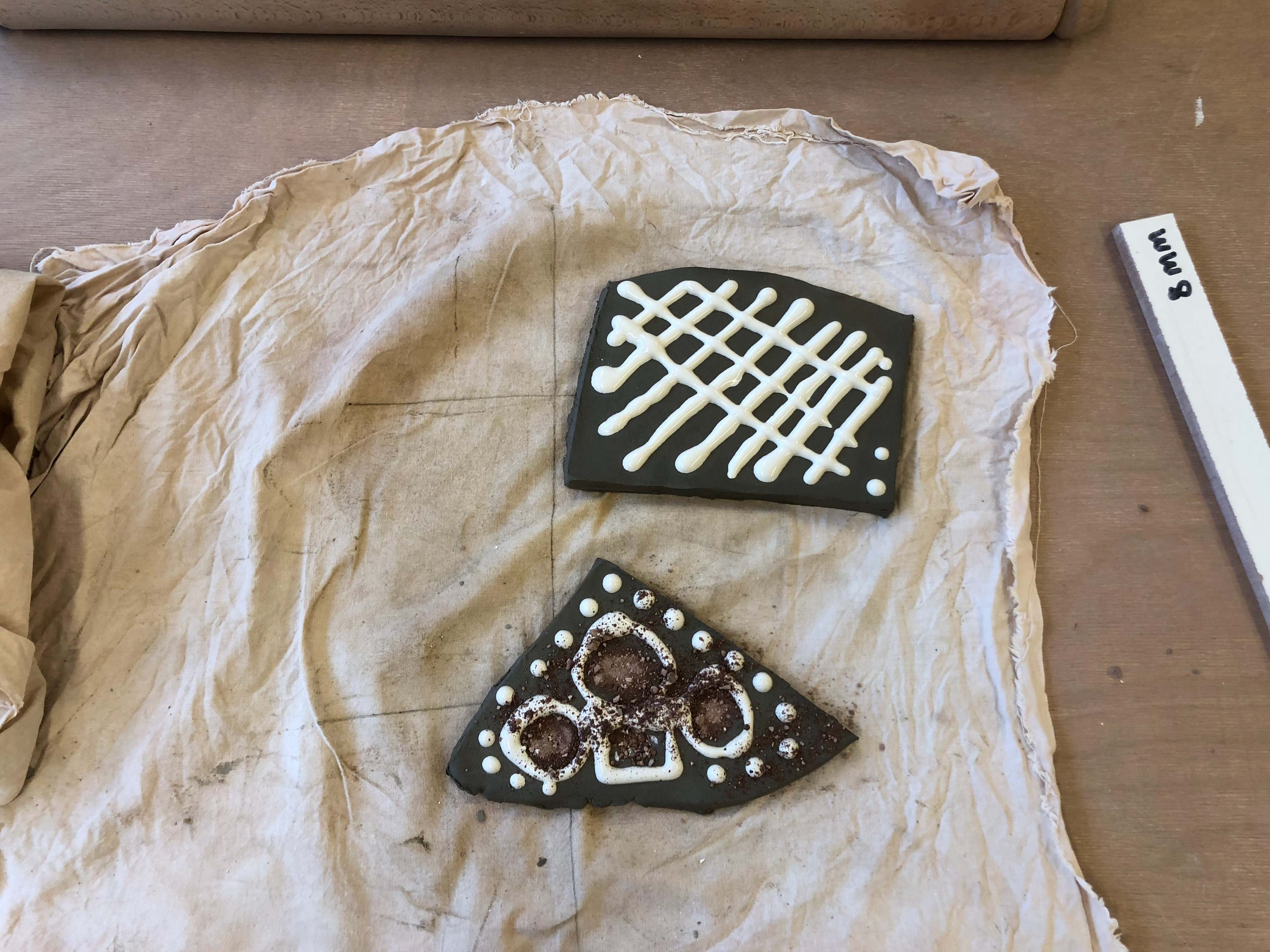 The top is a design about timing and how quick movement of the slip trail affect the outcome. The bottom is mixing the crushed clay with slip to form patterns.