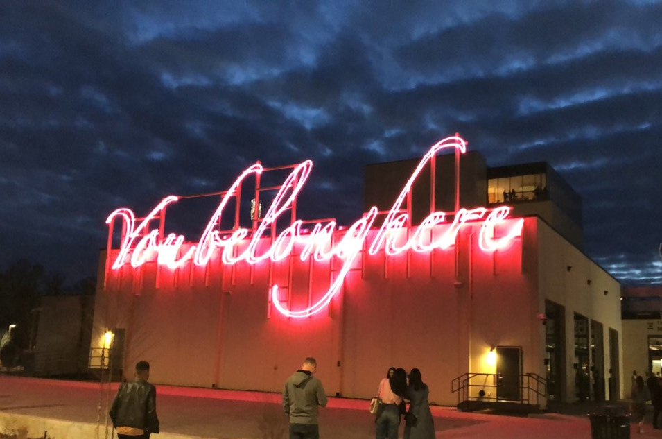 Bright pink neon sign that says "You belong here" on the side of a building.
