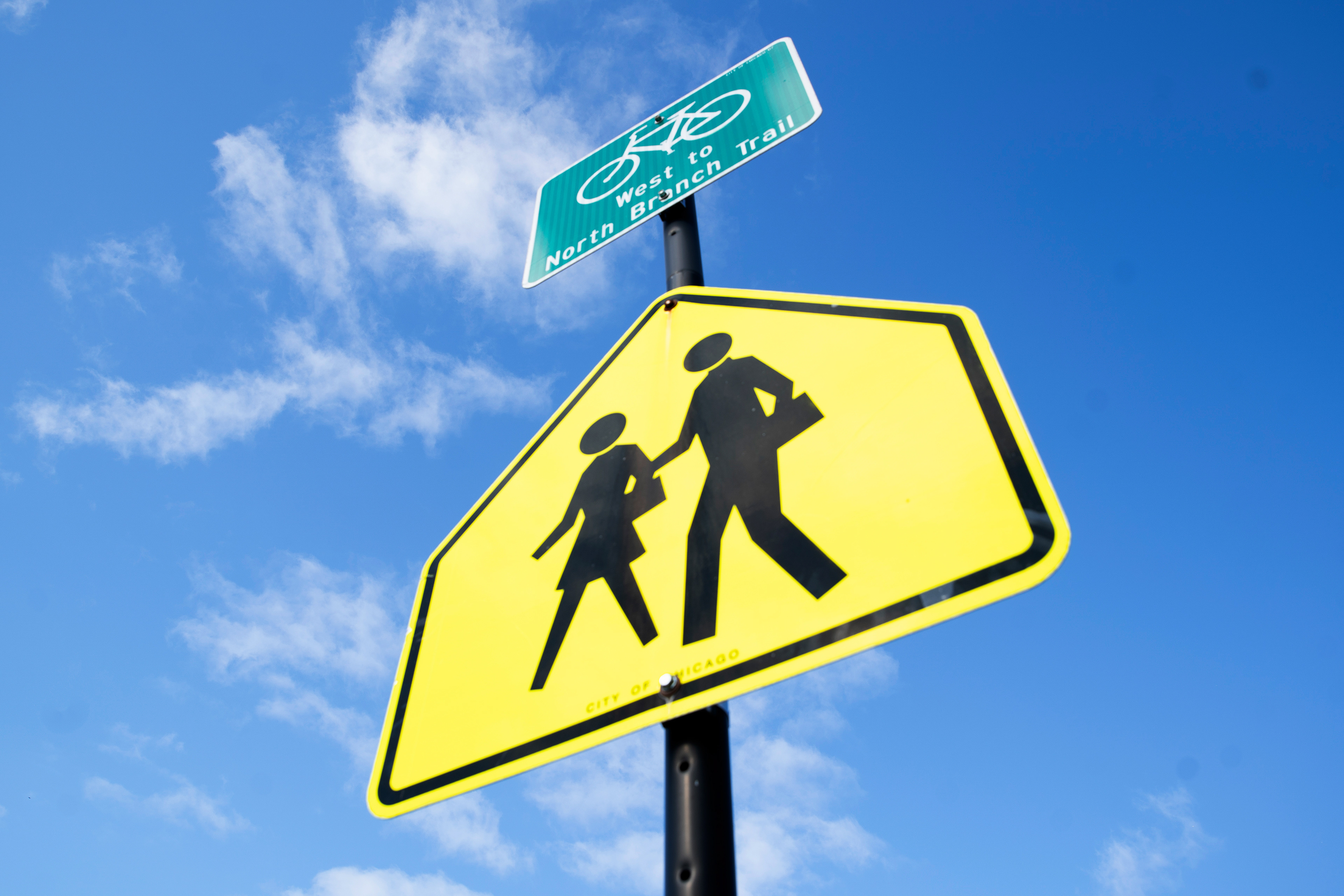 A school crosswalk sign marks a school-zone crosswalk at the corner of West Bryn Mawr Avenue and North Mozart Street approaching Jamieson Elementary School in Chicago on April 7, 2026. Crossing guards stand at these crosswalks near schools to help students cross the street and to encourage students to safely use crosswalks.