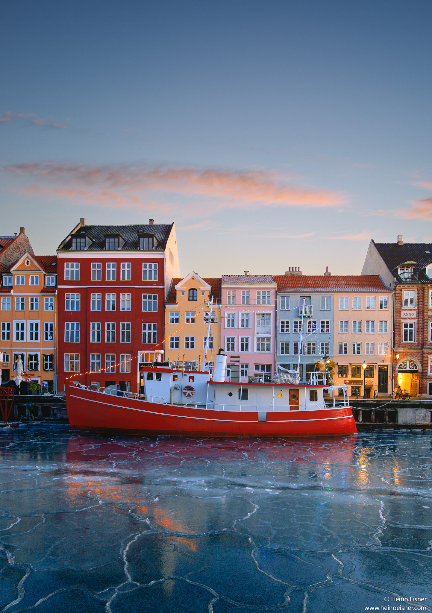 Nyhavn during winter, with ice on the water and a red boat and colourful houses